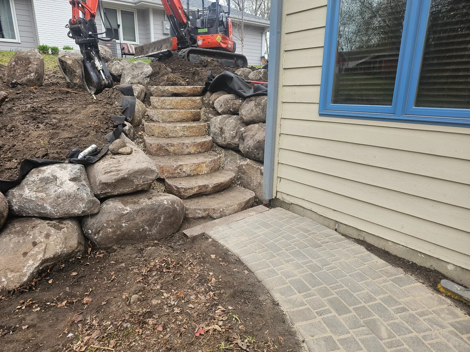 Boulder steps nearing completion with relaid paver walkway at base — Burnsville MN — Heritage Outdoors