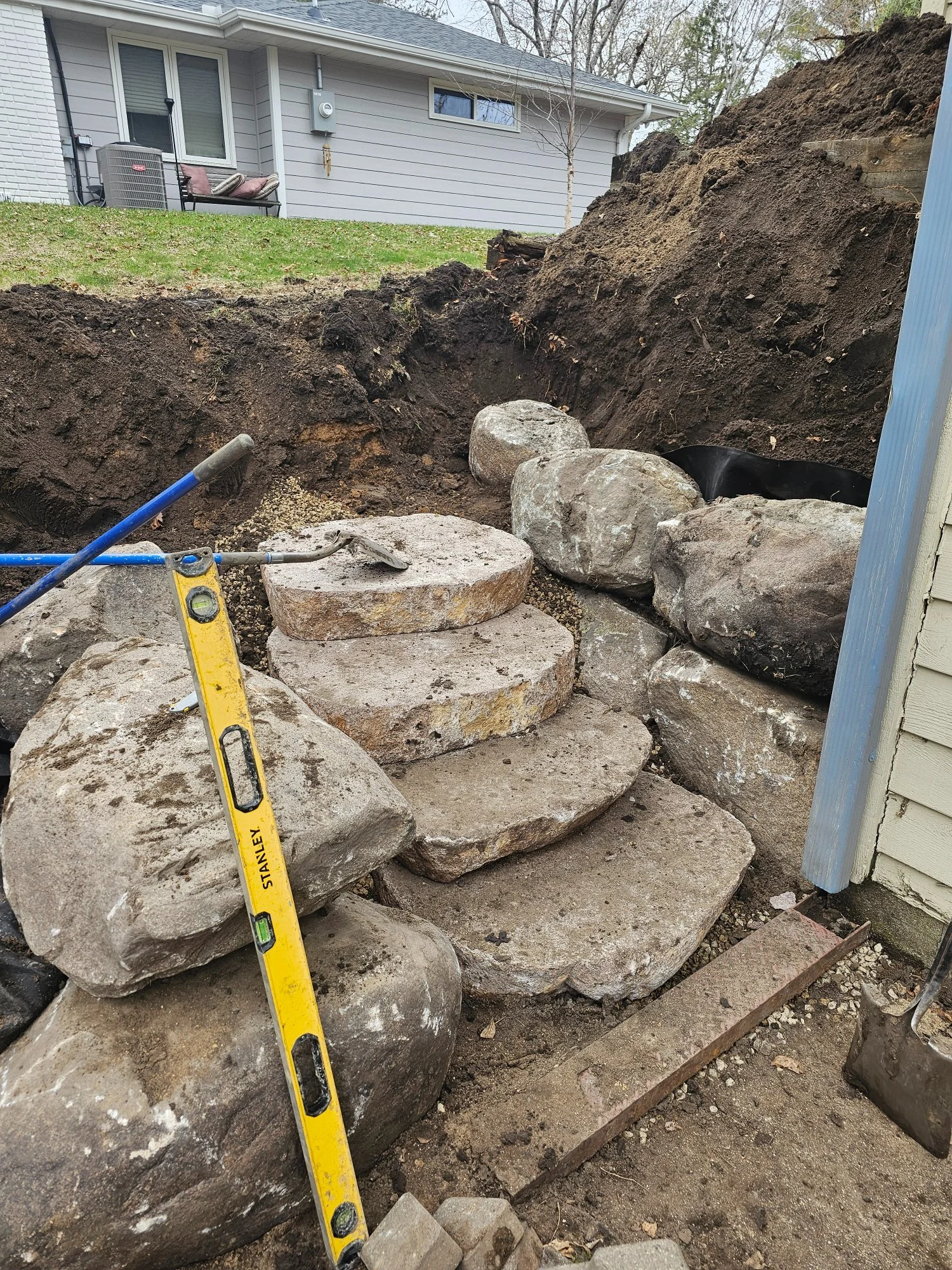 Cut granite boulder steps being set with level — Burnsville MN — Heritage Outdoors