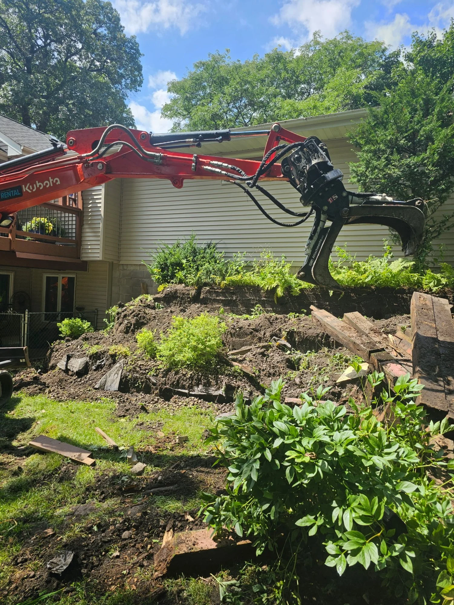 CMP grapple excavator tearing out rotting timber wall — Woodbury MN — Heritage Outdoors 2025
