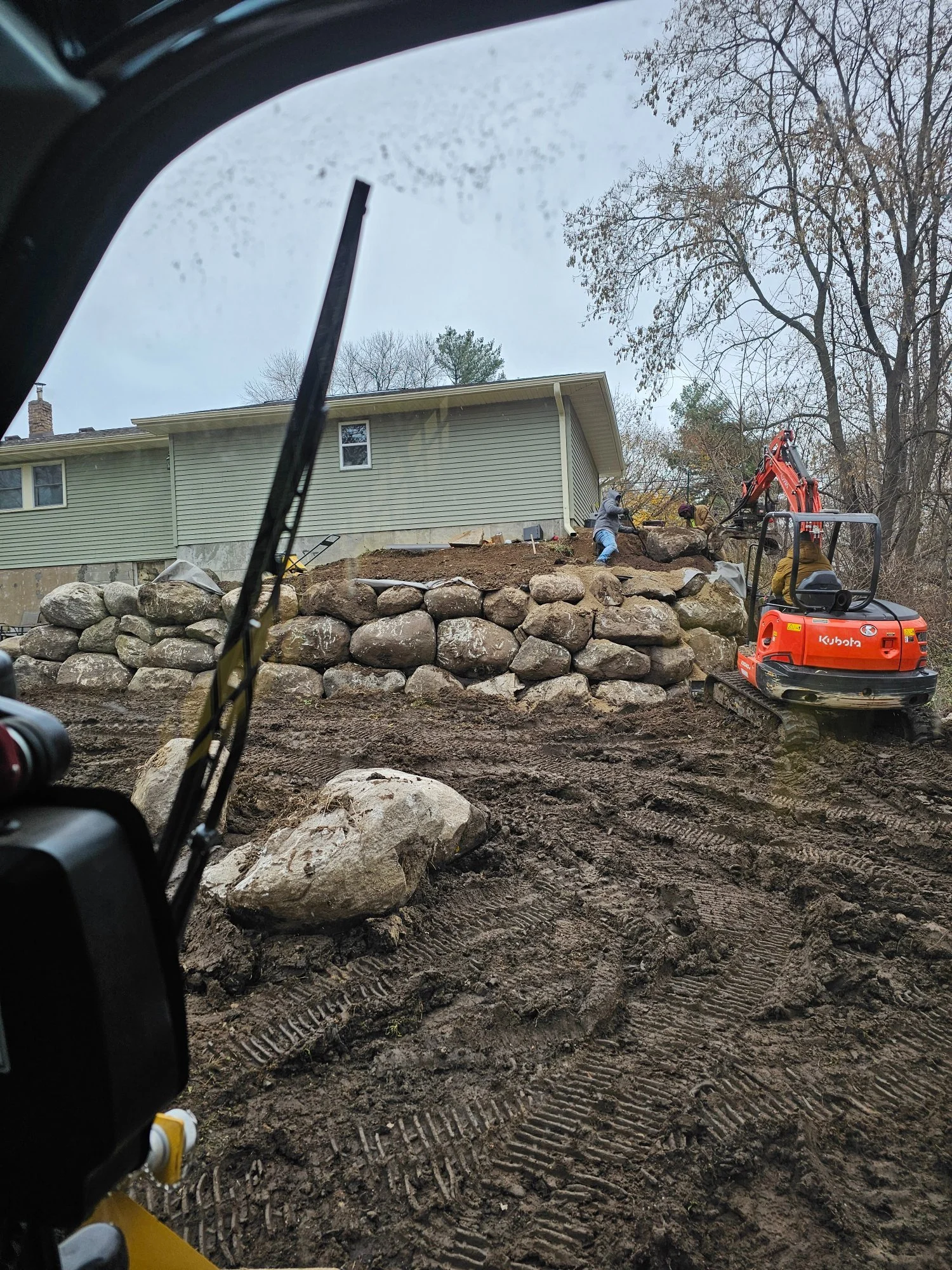 Fieldstone boulder wall installation behind garage — Lake Elmo MN — Heritage Outdoors Twin Cities