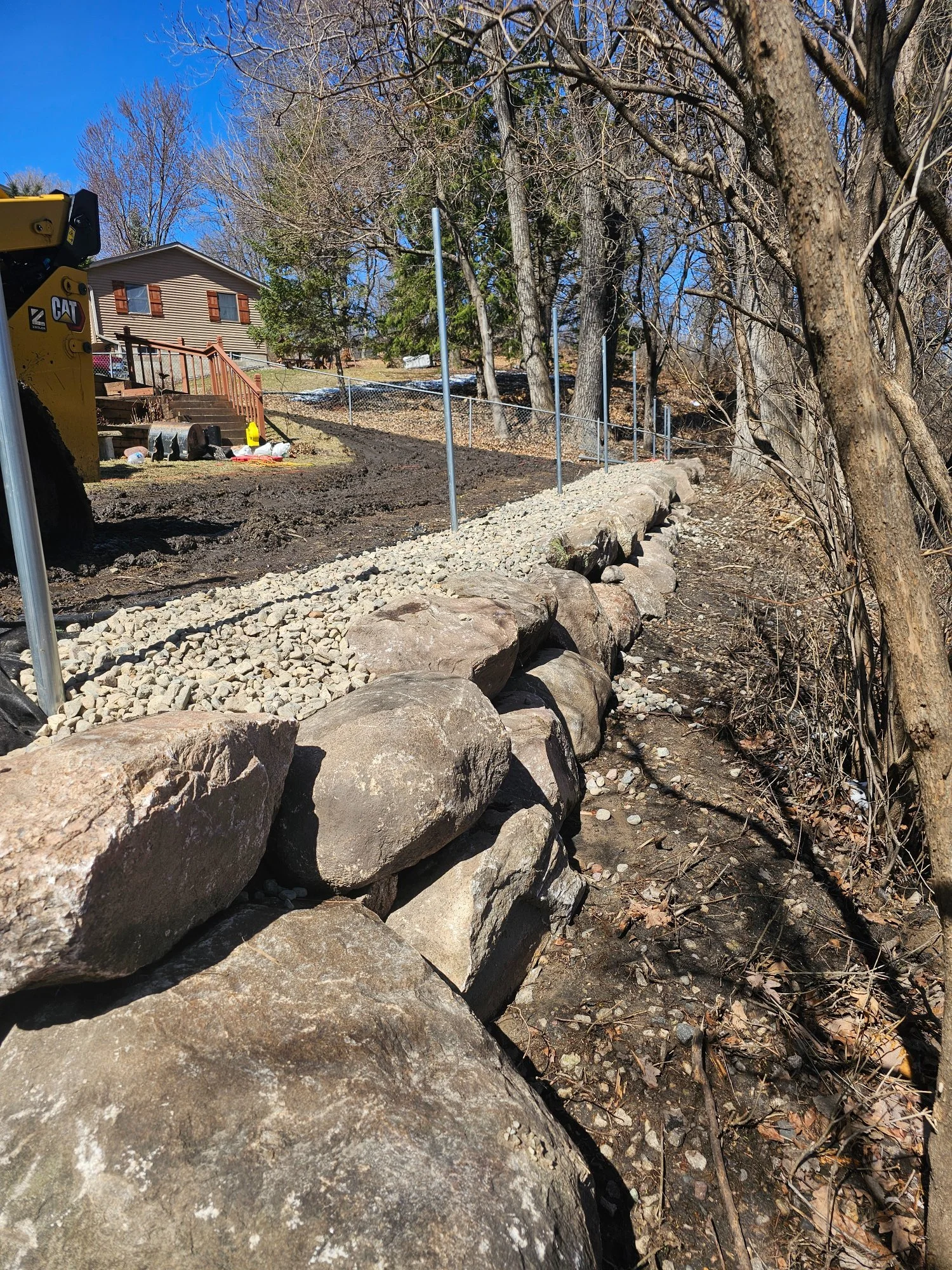 Completed boulder wall running full pond edge with gravel path — Woodbury MN — Heritage Outdoors 2025