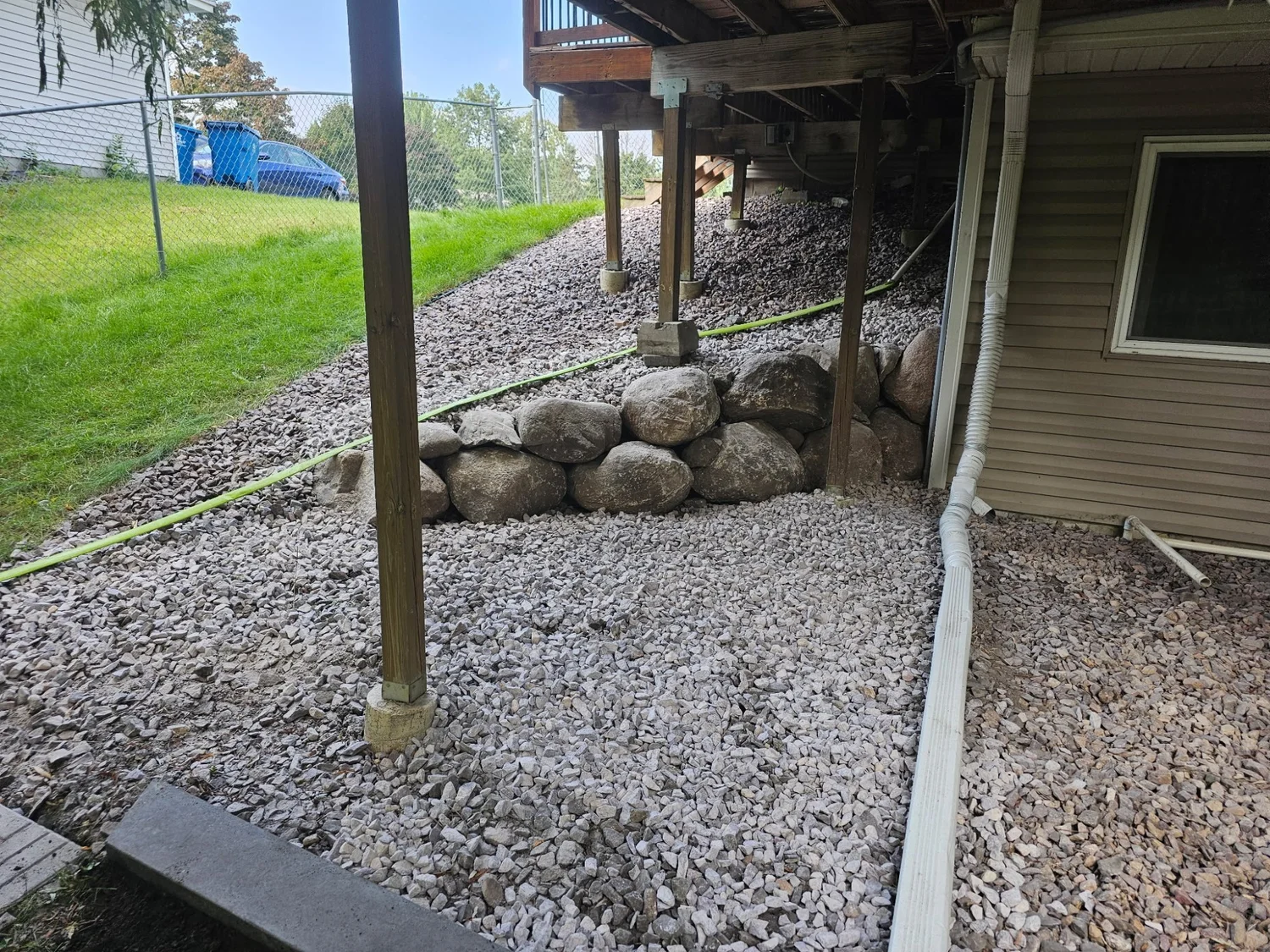 Completed natural boulder retaining wall along house in Centerville MN — timber wall replacement by Heritage Outdoors