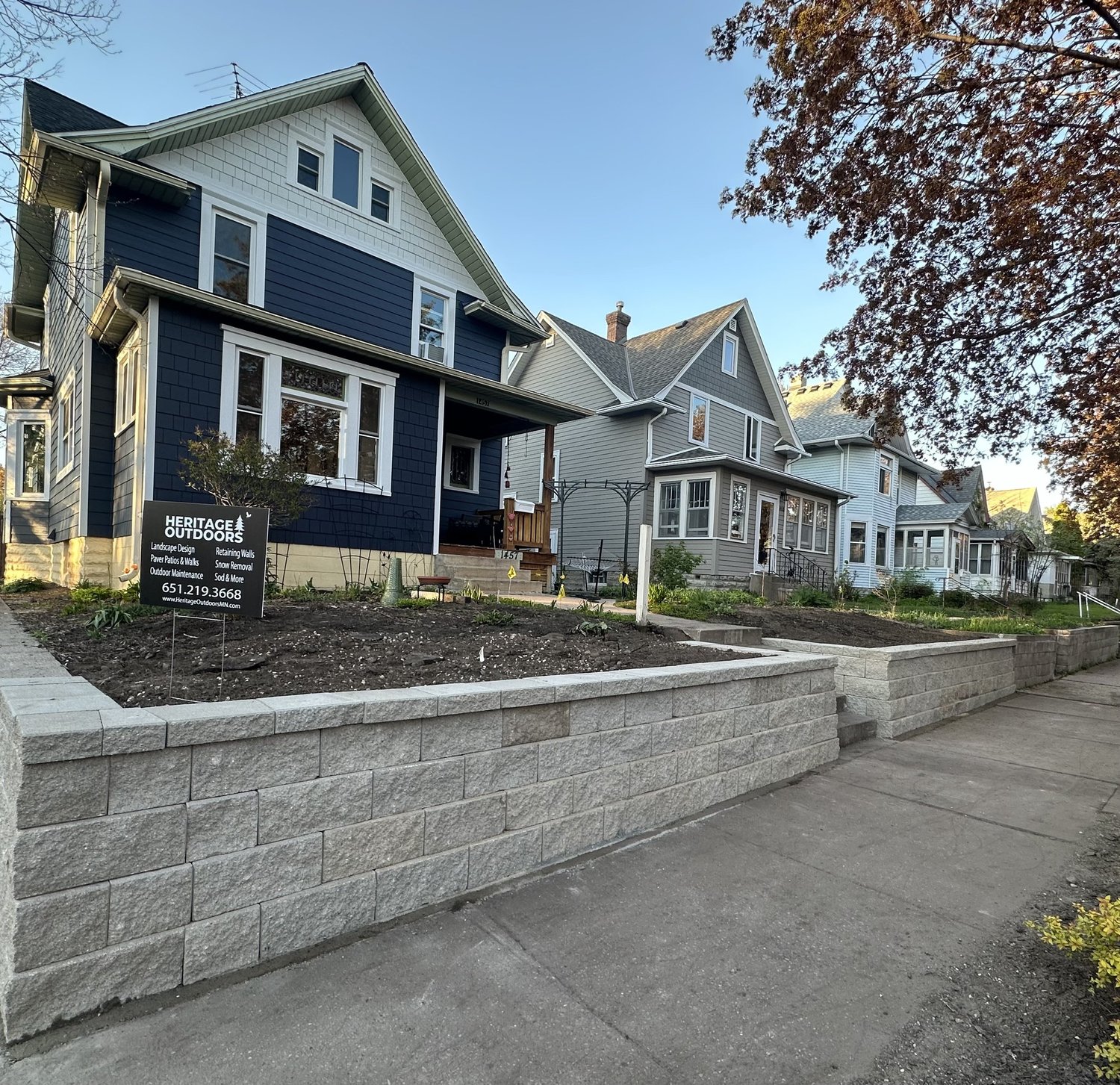 Completed Versa-Lok retaining wall street view with Heritage Outdoors yard sign — Hamline-Midway Saint Paul MN 2024