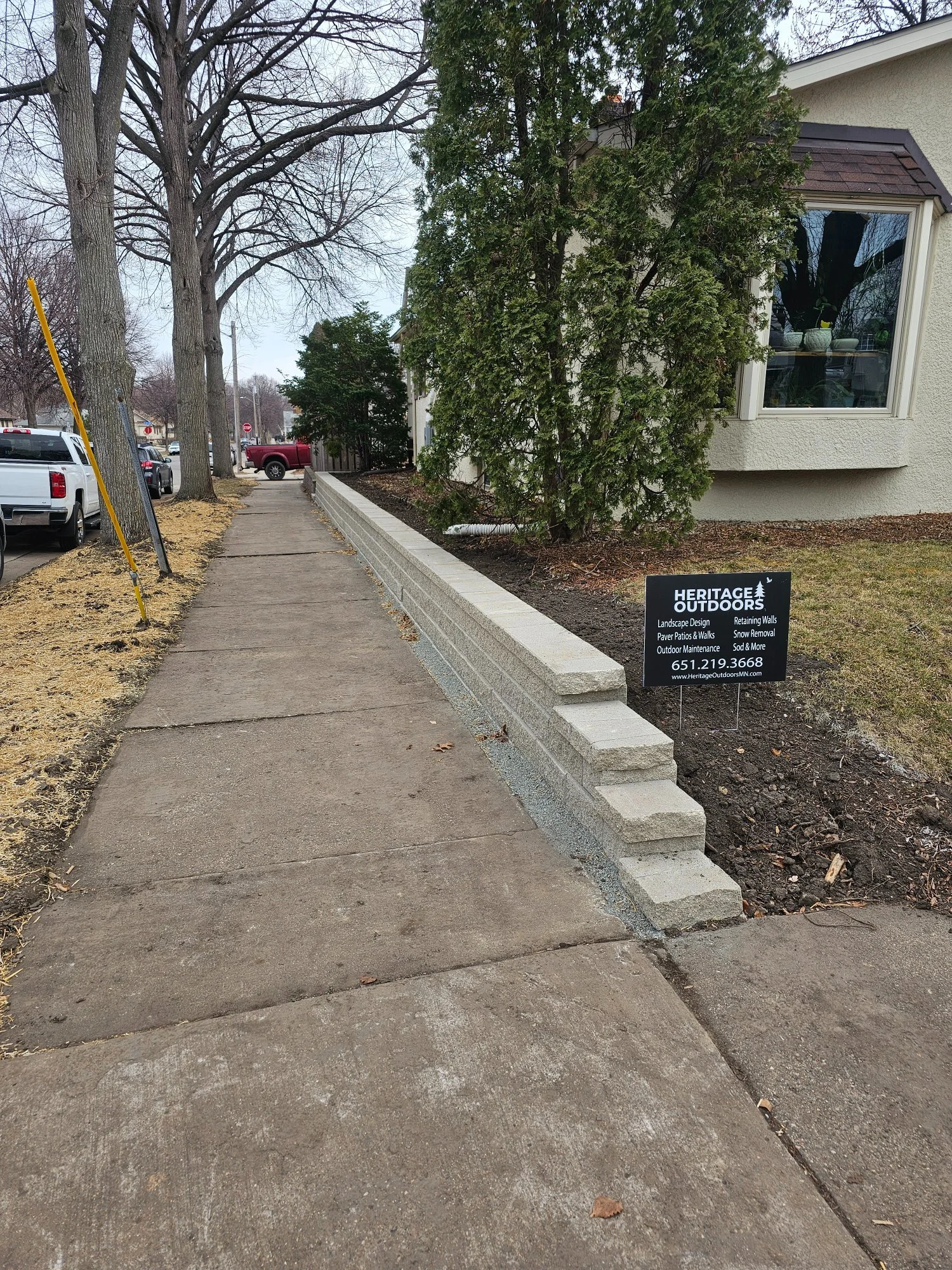 Completed Versa-Lok retaining wall with Heritage Outdoors yard sign — Longfellow Minneapolis MN — February 2024