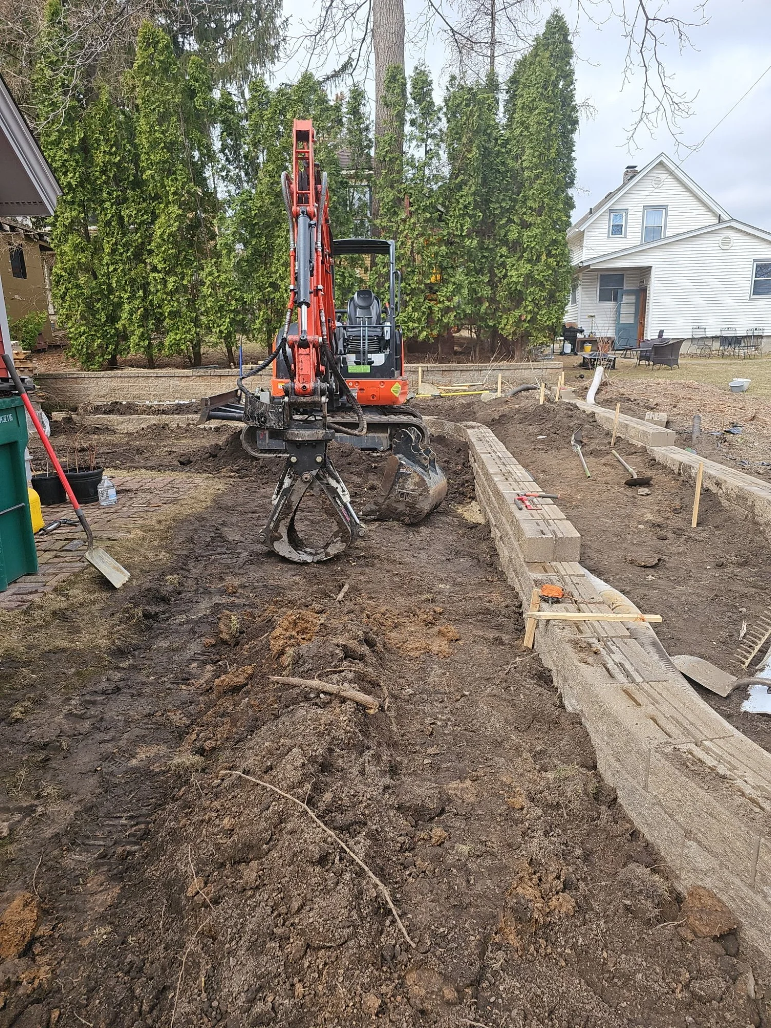 Kubota excavator prepping site for curved Versa-Lok planter boxes — Stillwater MN — Heritage Outdoors