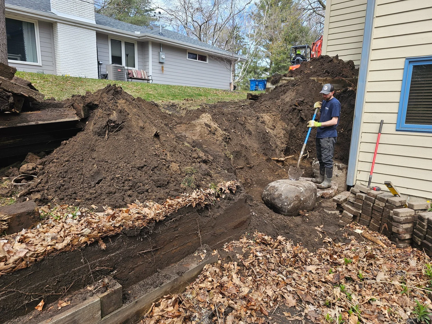 Timber retaining wall demolition in progress — Burnsville MN — Heritage Outdoors crew and excavator