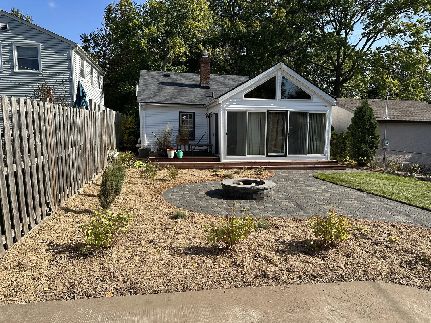 Completed backyard patio with fire pit and garden from house view — Como Park Saint Paul — Heritage Outdoors 2025