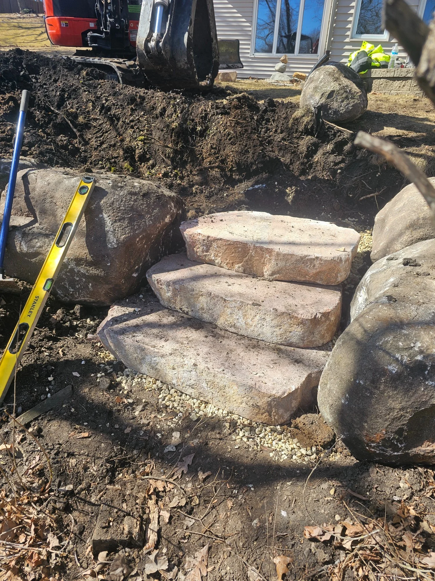 Natural stone steps being set for pond access with level — Woodbury MN — Heritage Outdoors 2025