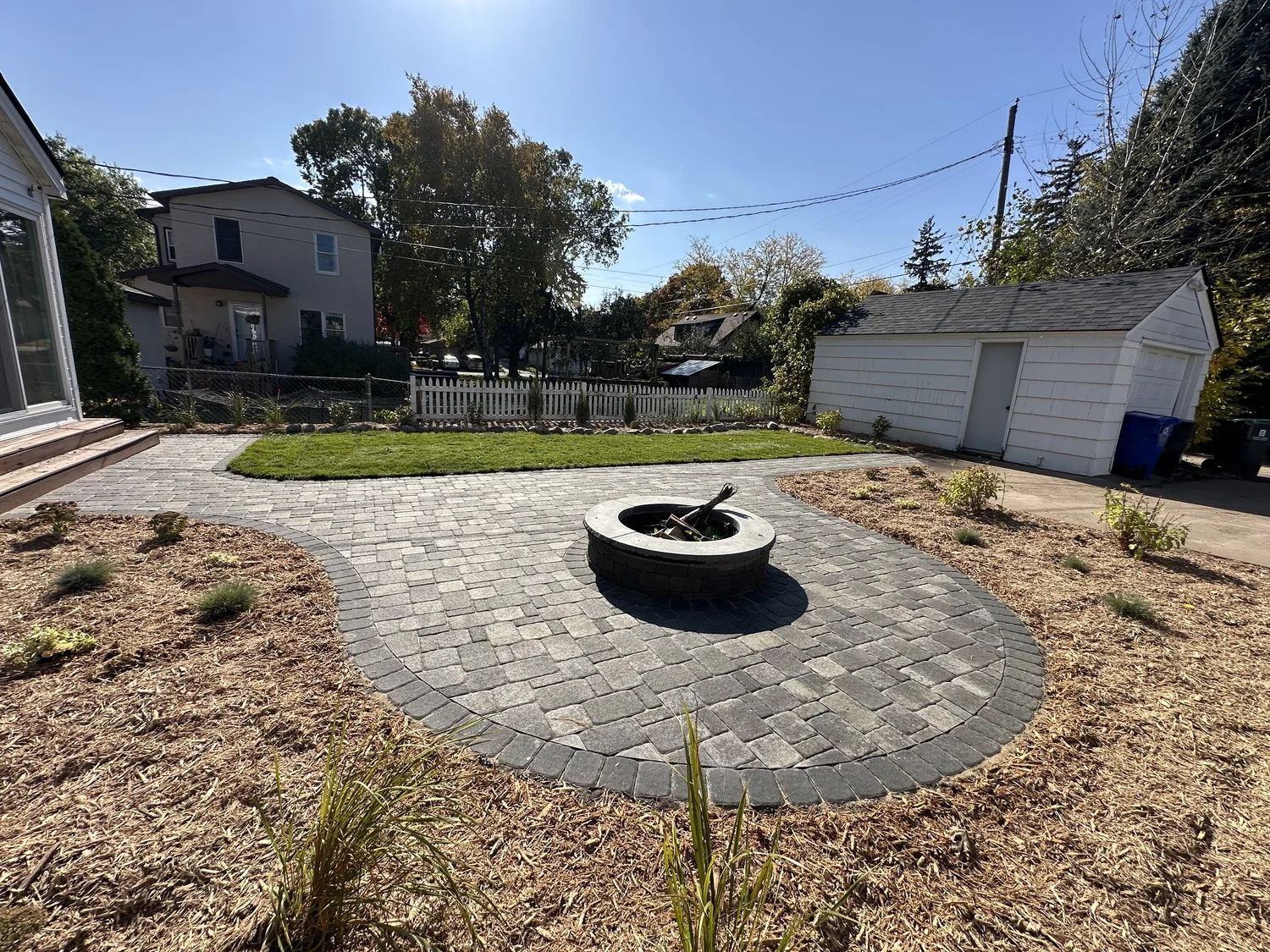 Completed paver patio with fire pit centered and mulch beds — Como Park Saint Paul — Heritage Outdoors 2025