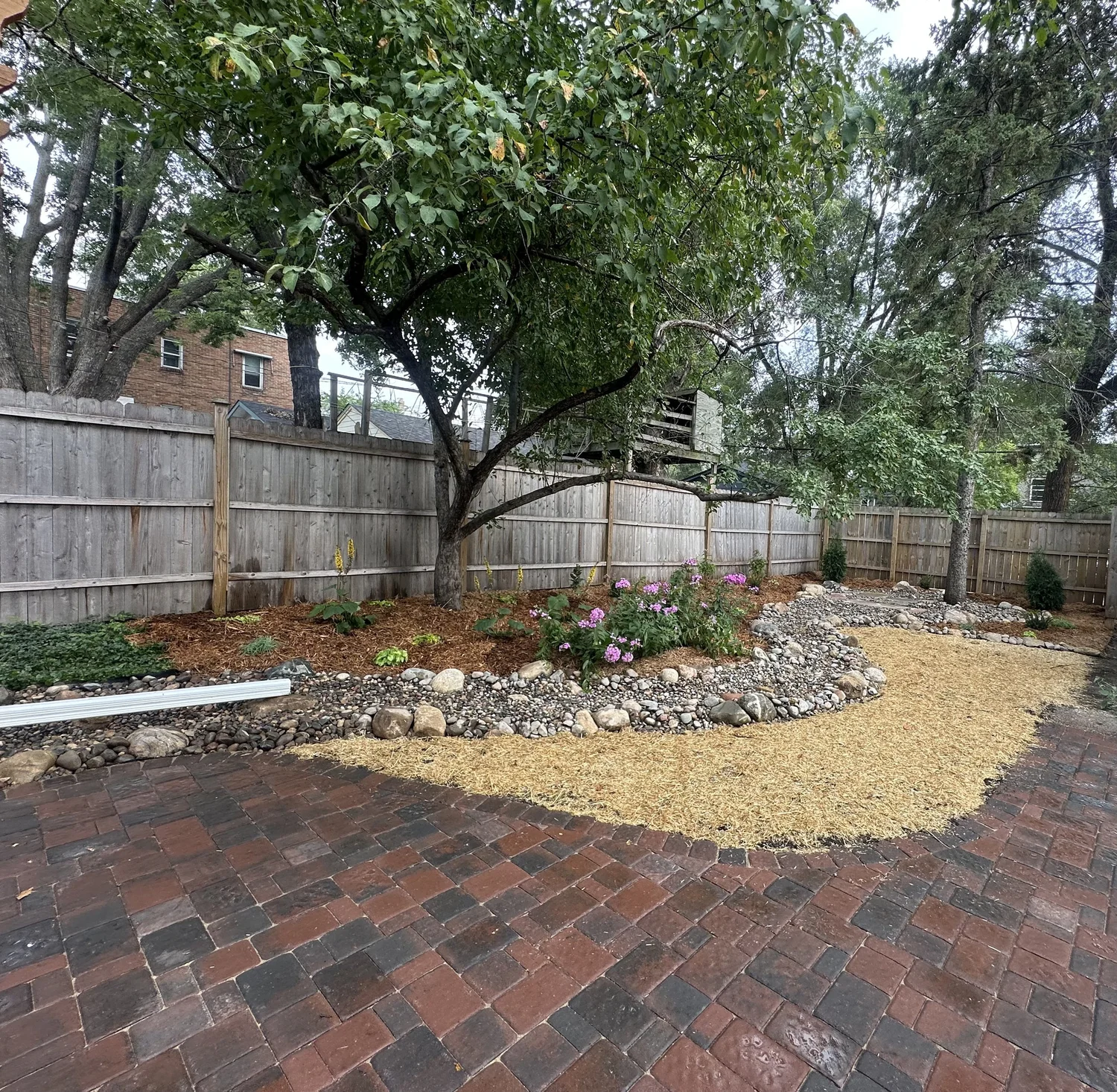 Dry creek bed leading to flagstone bench with pollinator garden — Hamline-Midway Saint Paul MN — Heritage Outdoors 2025