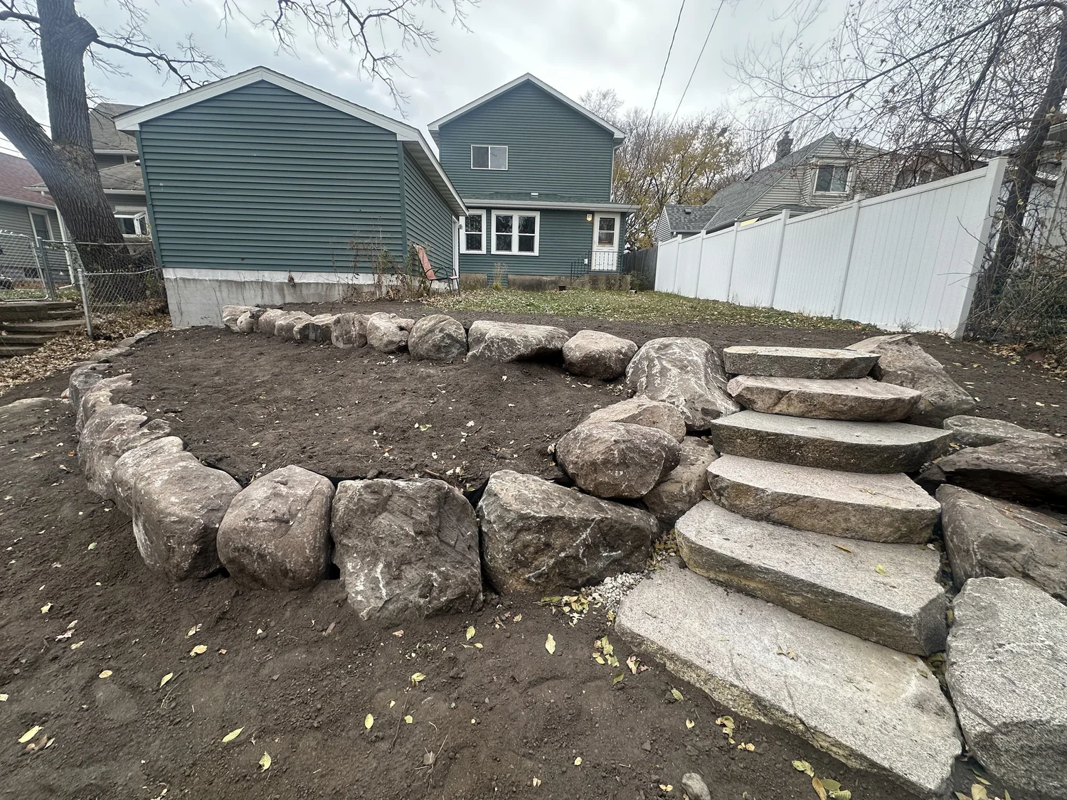 Curved tiered boulder wall and natural stone steps — Saint Paul MN — Heritage Outdoors 2025