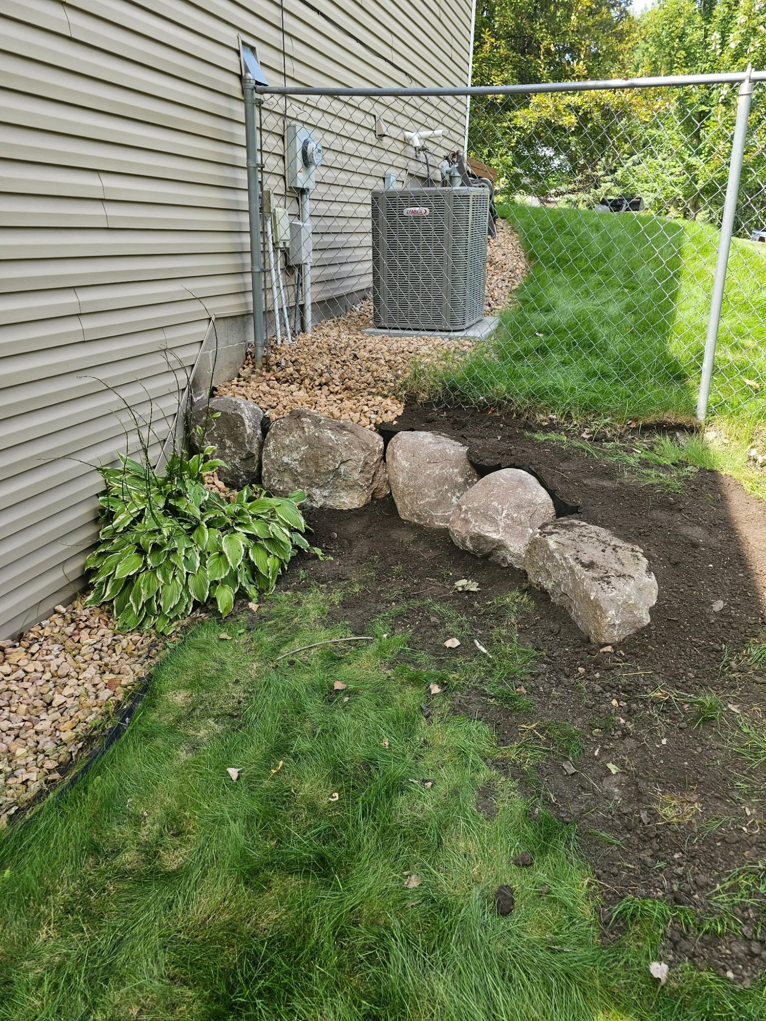 Boulder wall installed under second-story deck in Centerville MN with clean gravel surface — Heritage Outdoors