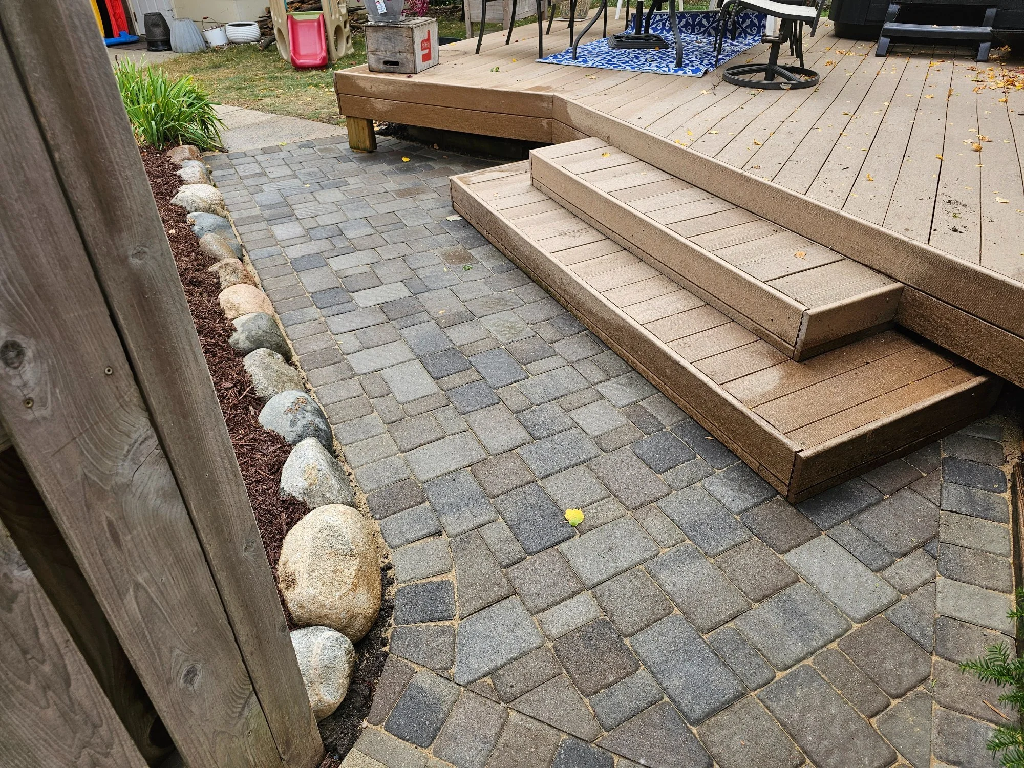 Completed Willow Creek Cobblestone paver landing at deck stairs with boulder edging — Longfellow Minneapolis MN — Heritage Outdoors 2024