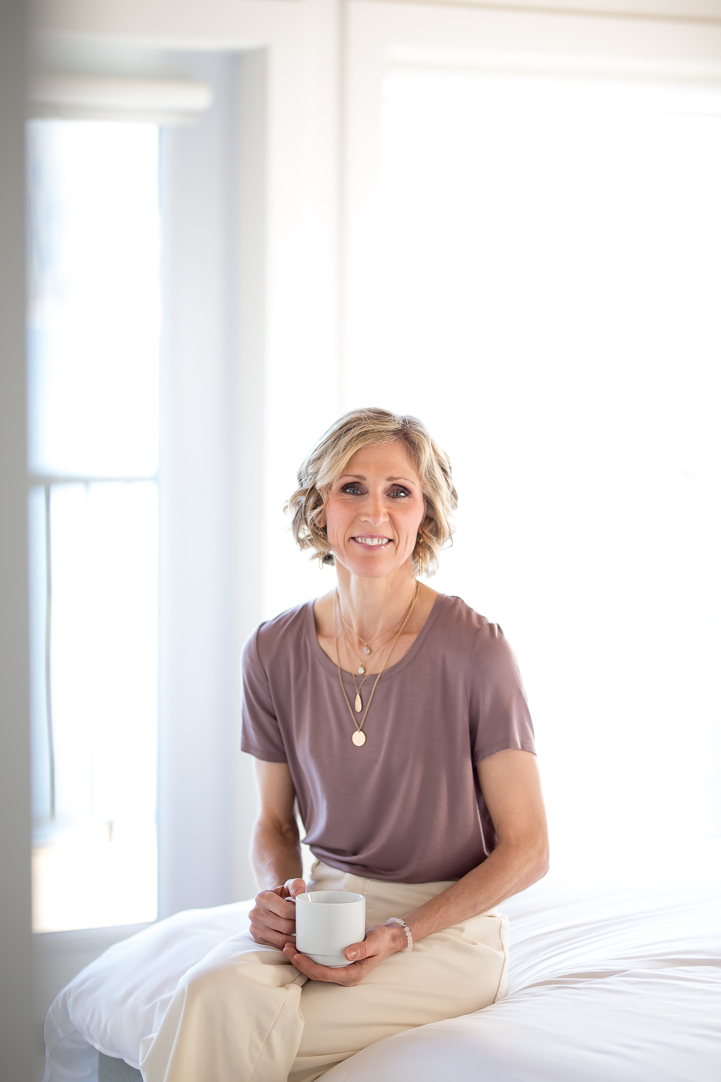 Woman sitting on bed holding a mug