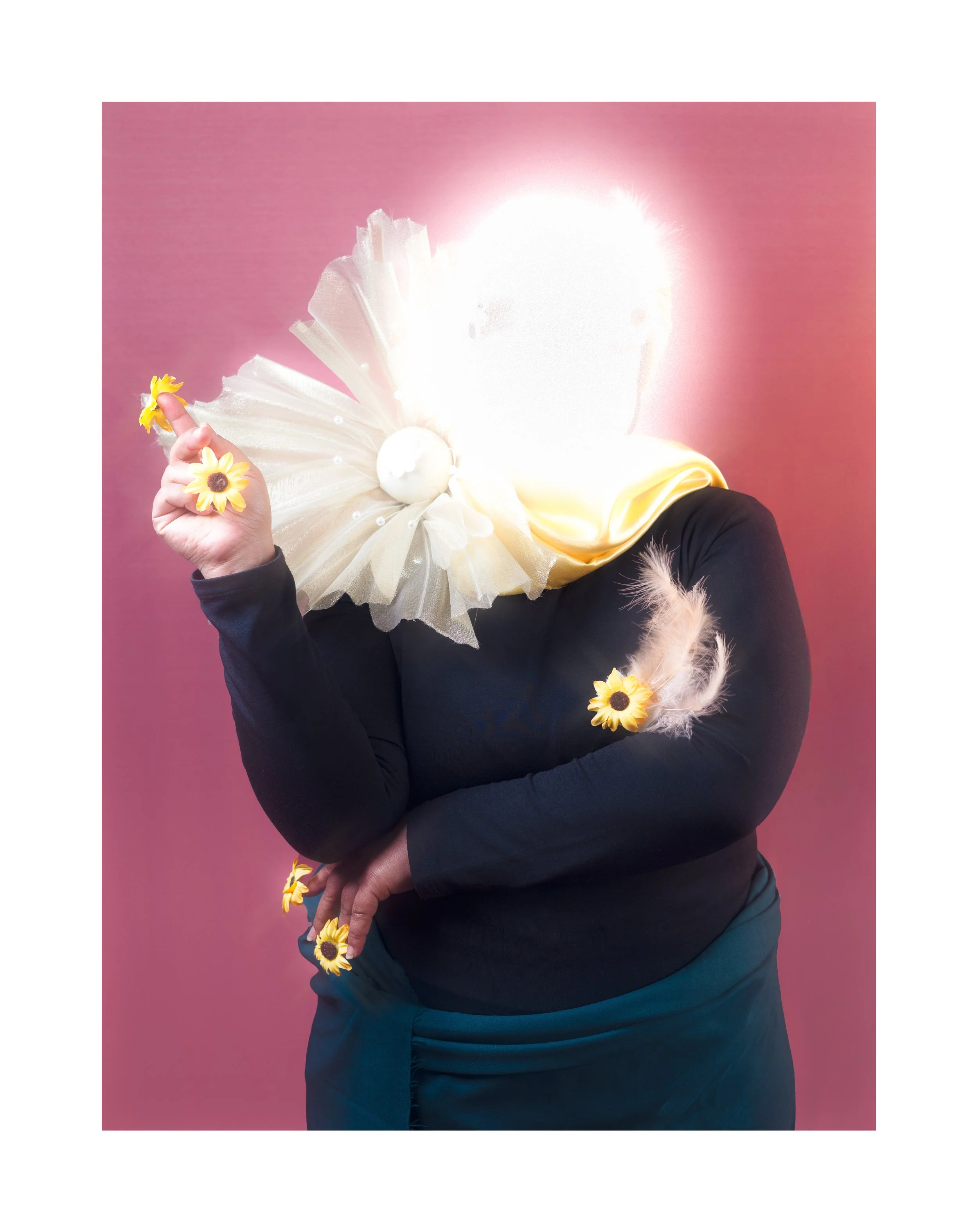 Personne avec un visage flou ou masqué, portant un haut noir et un foulard jaune, décorée de fleurs de tournesol et de plumes, sur un fond rose.