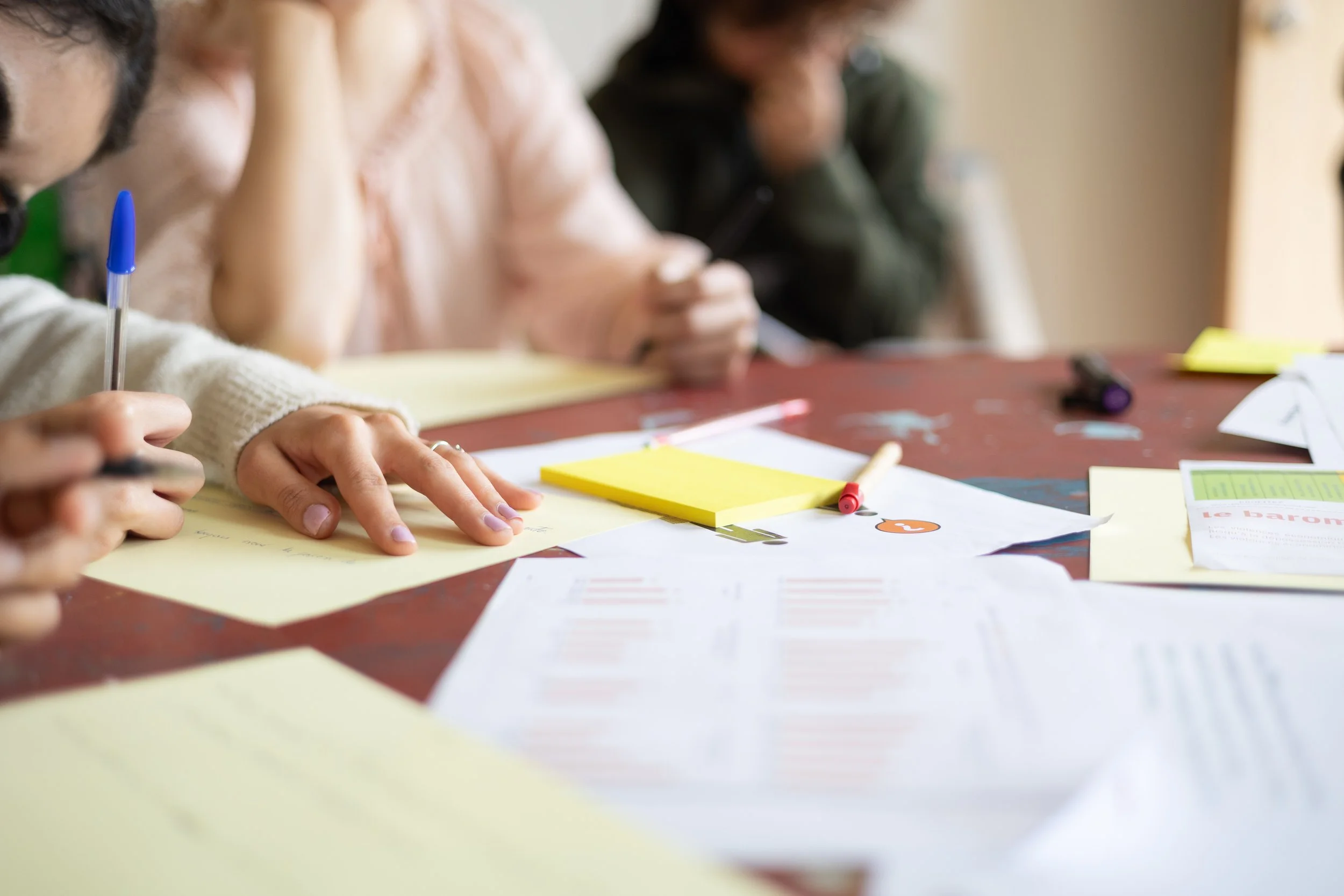 Groupe de personnes travaillant autour d'une table avec des papiers, des stylos et des notes adhesifs.