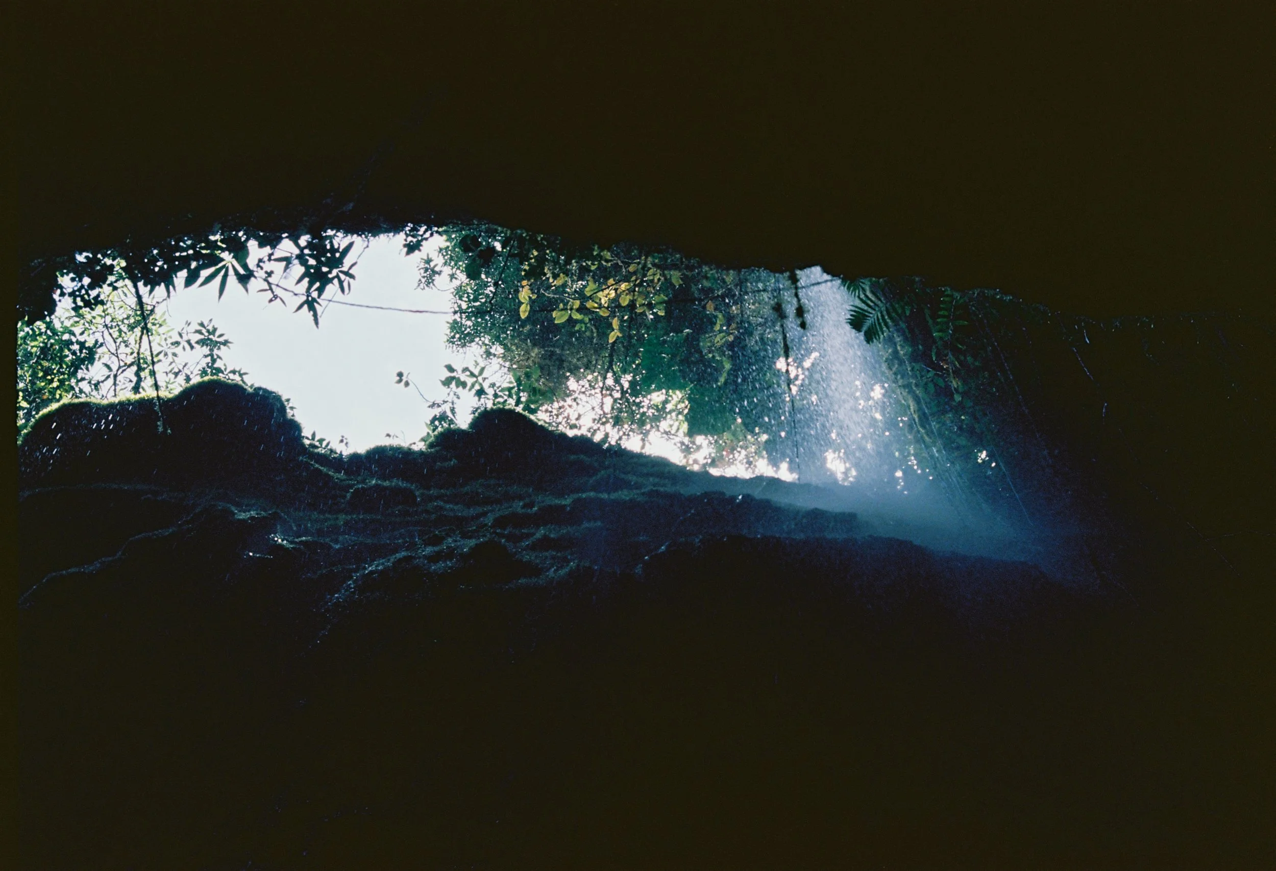 Photo en Colombie. Vue d'une ouverture dans une grotte, avec la lumière du soleil et la végétation visible à l'extérieur.
