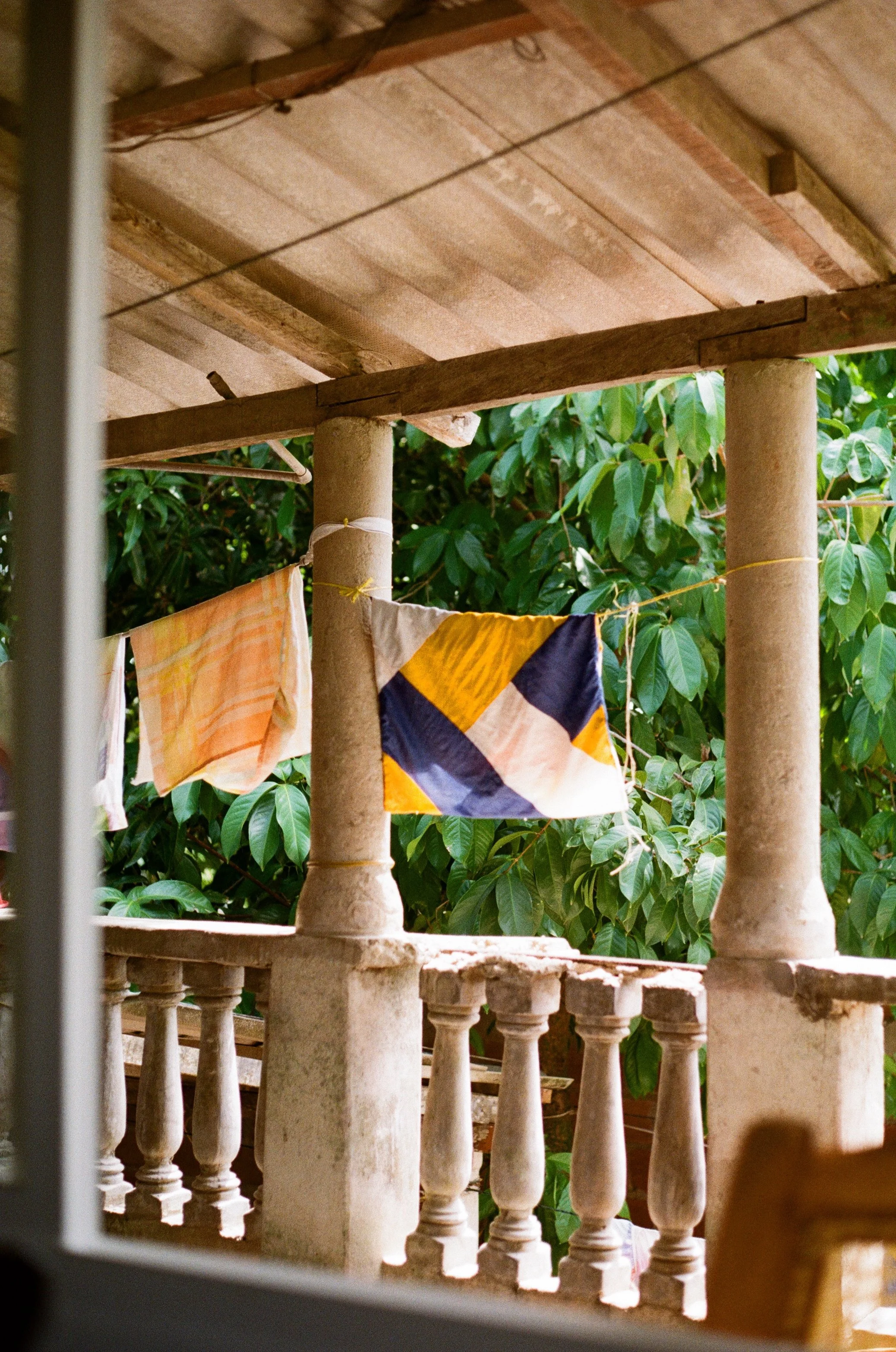Photo en Colombie. Terrasse en pierre with balustrades, des vêtements colorés suspendus pour sécher, entourée de verdure dense.