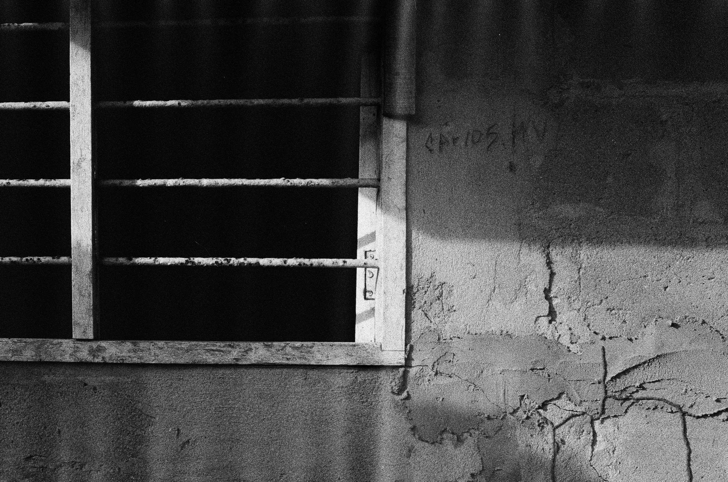 Murs en béton fissurés et une fenêtre en fer rouillé, fond sombre