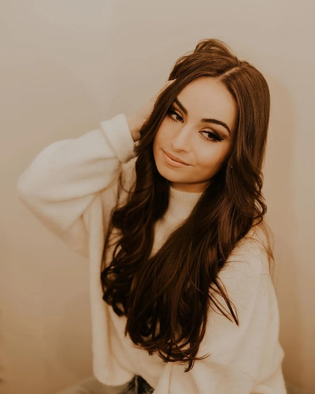 With her beautiful, lengthy brown hair cascading down, a woman sits gracefully, radiating confidence and charm