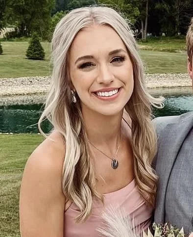 A wedding guest posing for a photo, her natural makeup adds a touch of beauty to her overall appearance