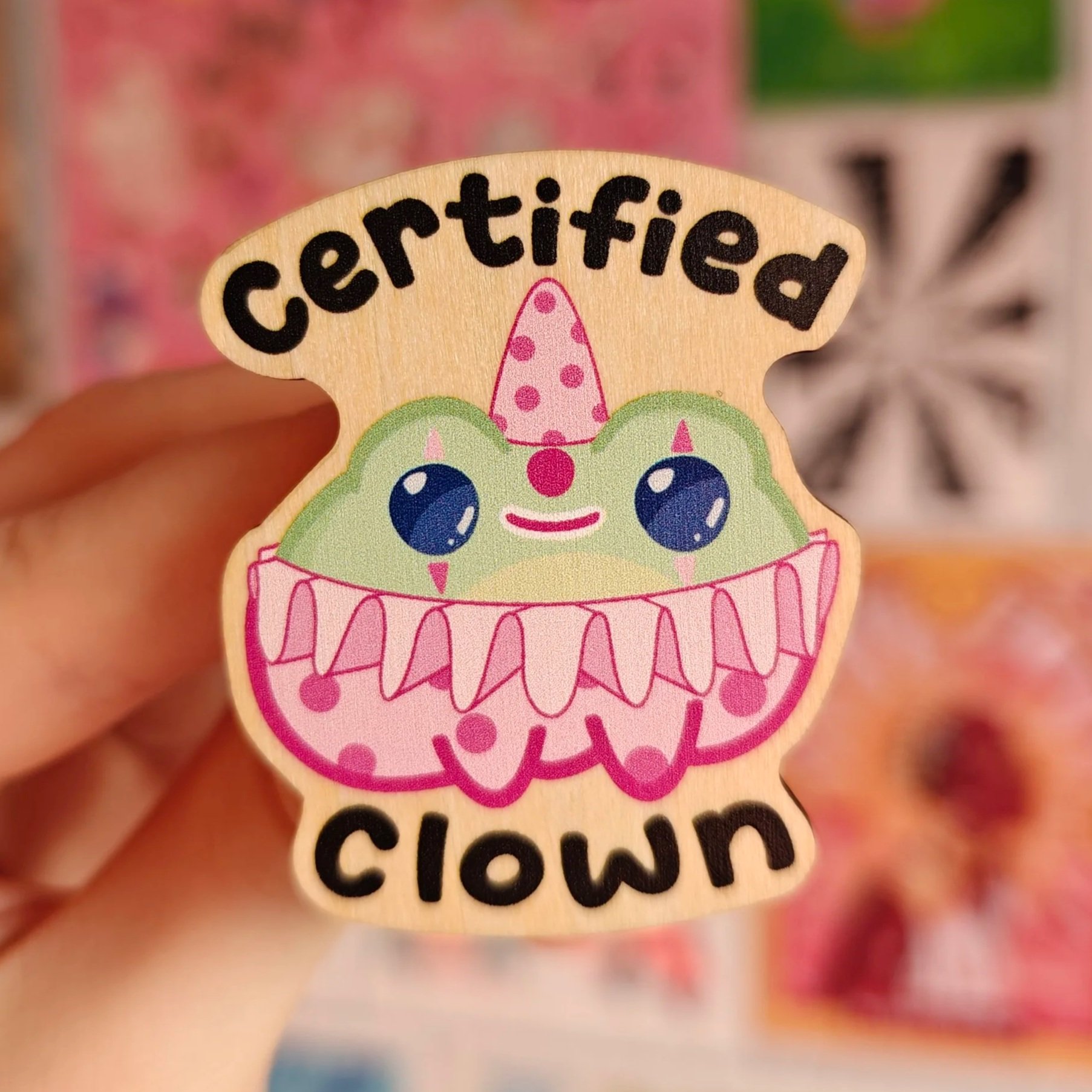 A colorful sticker of a cute frog dressed as a clown with a pink ruffled collar and wearing a pink polka-dot hat, with the words 'certified clown' written above and below.
