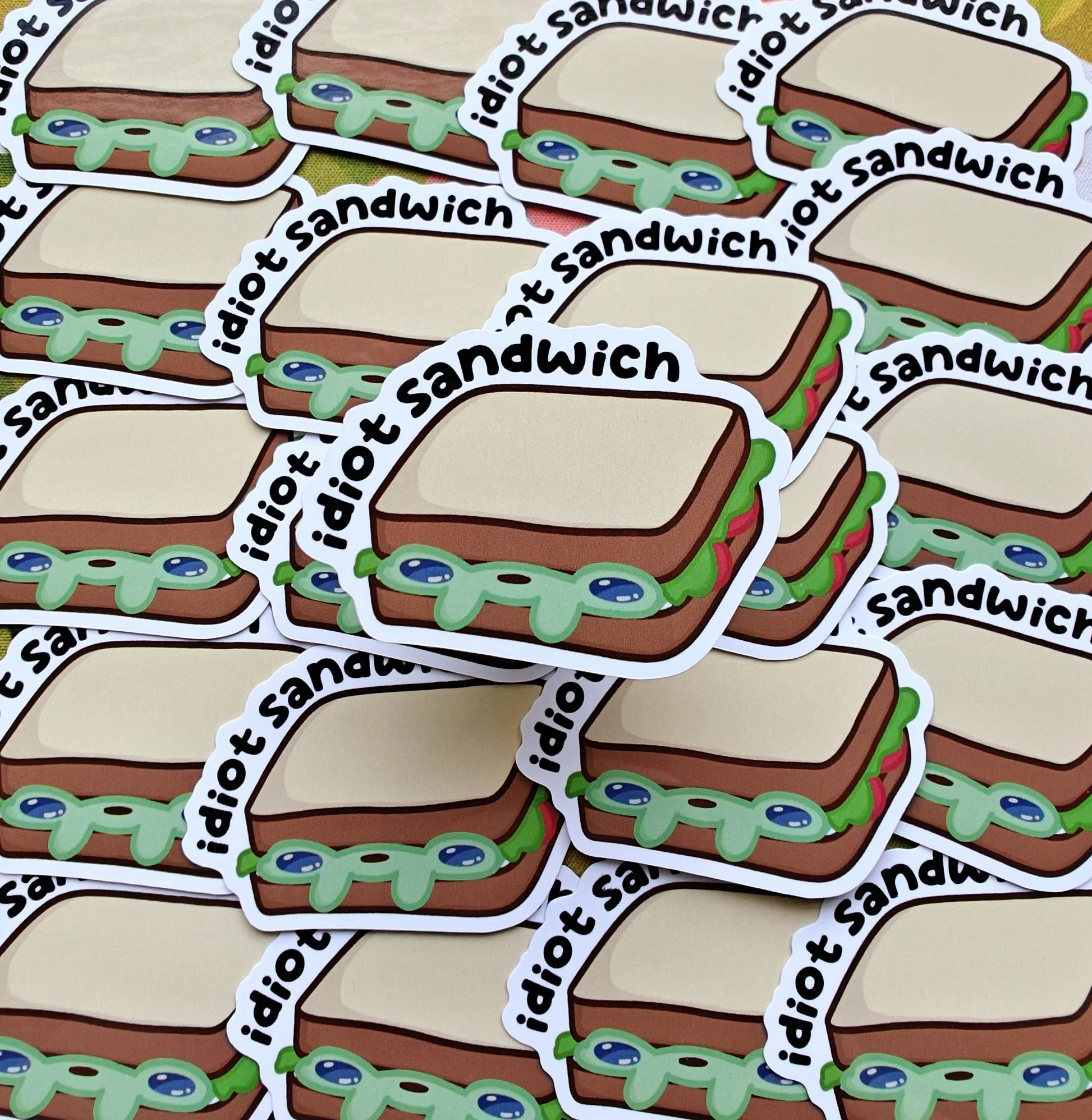 Multiple stickers of a cartoon-style sandwich with lettuce, tomato, and mayonnaise, labeled 'idiot sandwich.'