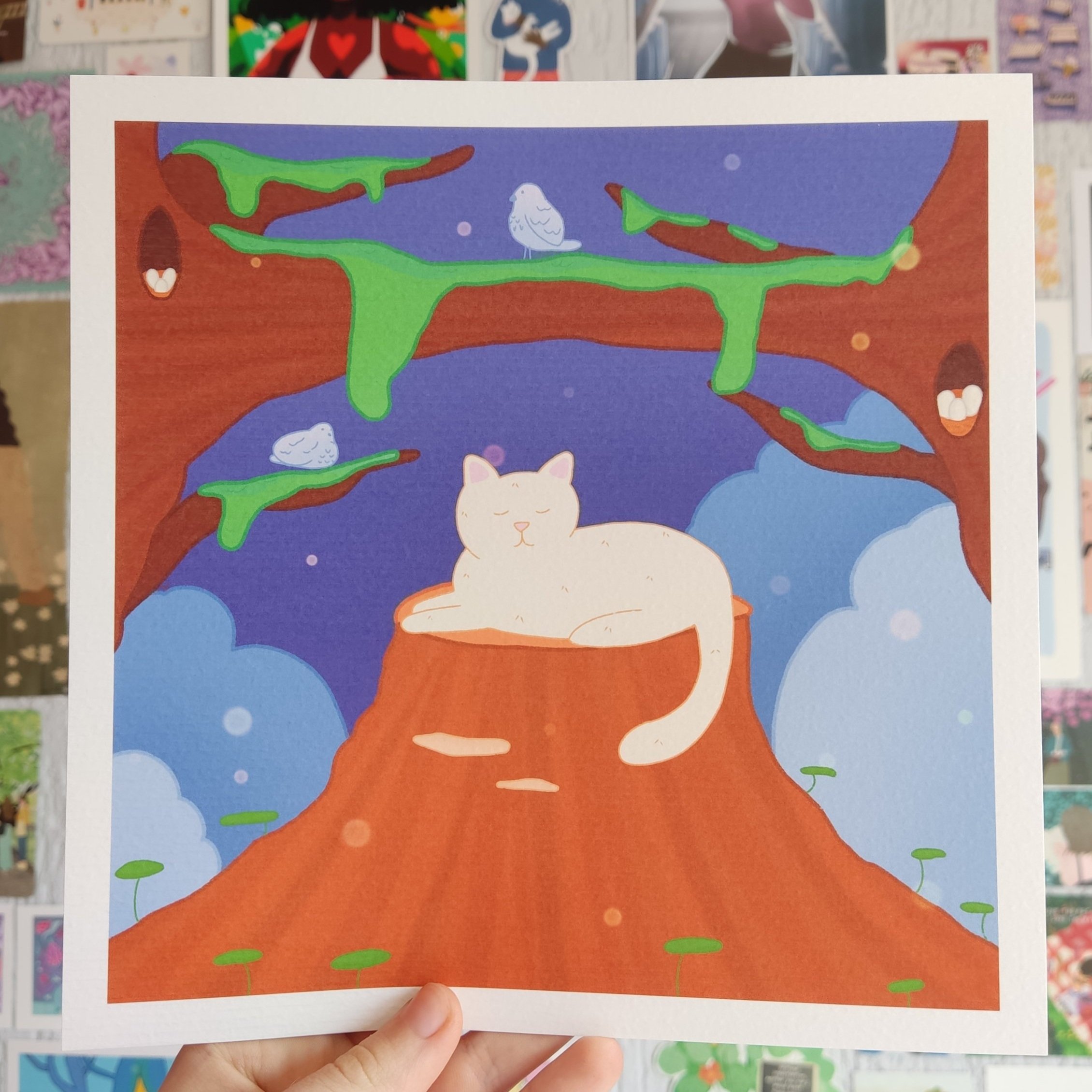 A cartoon illustration of a white cat sleeping on a tree stump with a large ash tree with green moss in the background, blue sky with clouds and small purple and white dots, and two small birds sitting on branches.