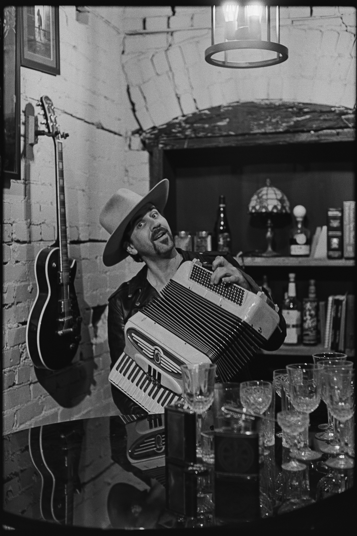 Ash Dudney wearing a western-inspired custom fedora by Til Death Hat Company while playing accordion at the bar in West Ybor, Tampa, Florida.