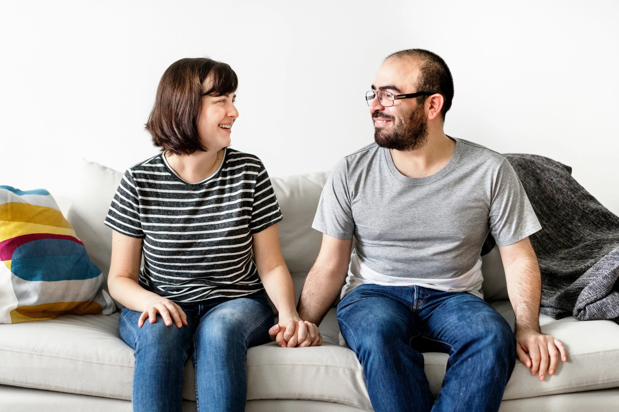 A couple sitting close and holding hands on a couch, illustrating trauma-informed couples therapy focused on healing together and rebuilding emotional safety in Fair Oaks couples therapy.