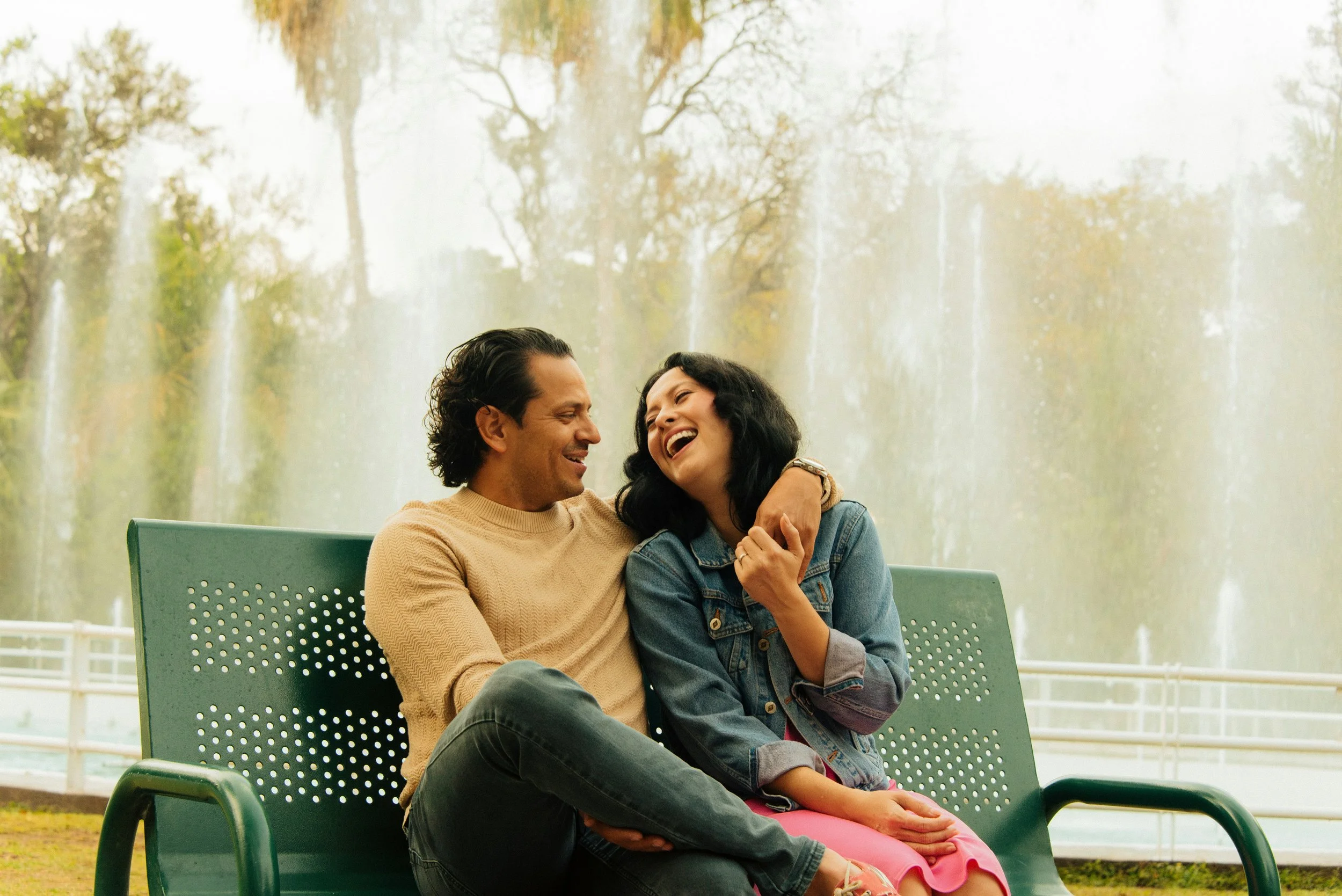 A couple sitting close together and laughing on a park bench, illustrating how healing childhood trauma in adults through Sacramento trauma therapy can support healthier trauma and relationships.