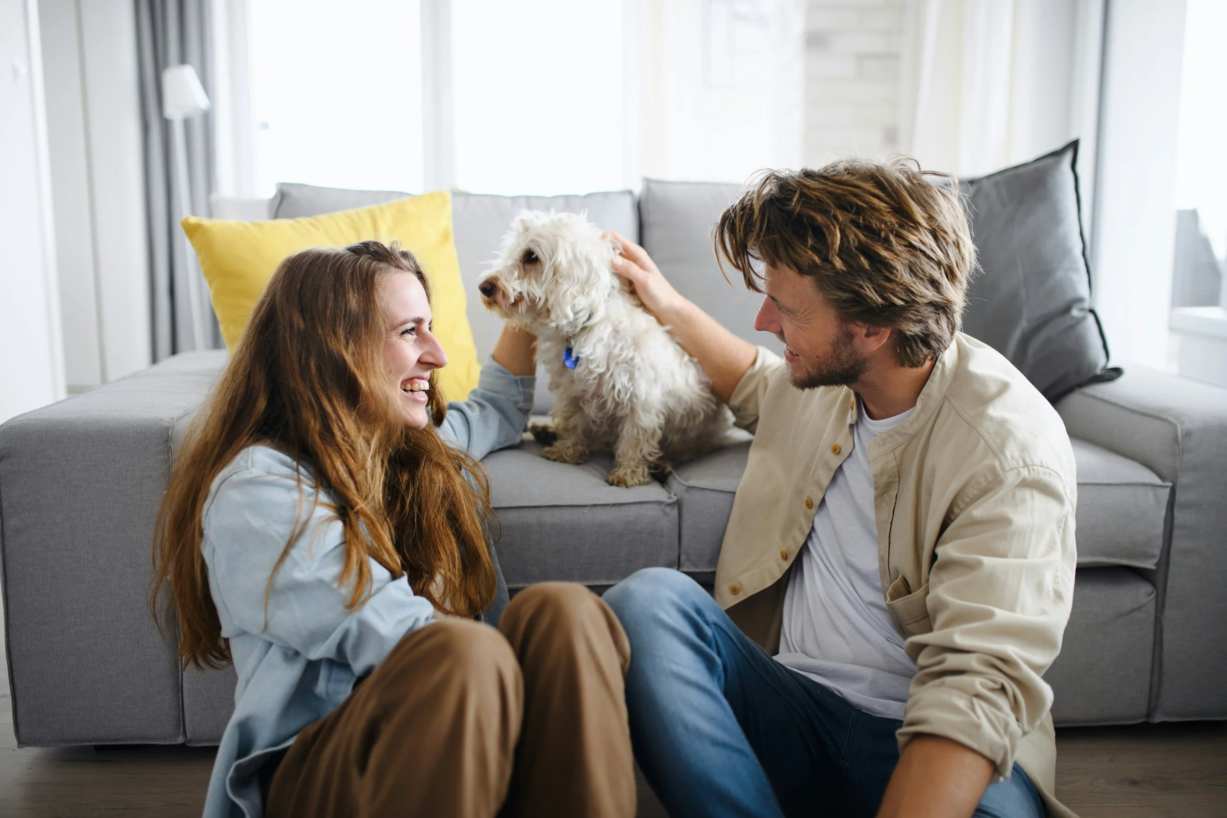 A couple sitting together on the floor with their dog, illustrating warmth, safety, and trauma healing support fostered through compassionate relationships and couples therapy Sacramento.