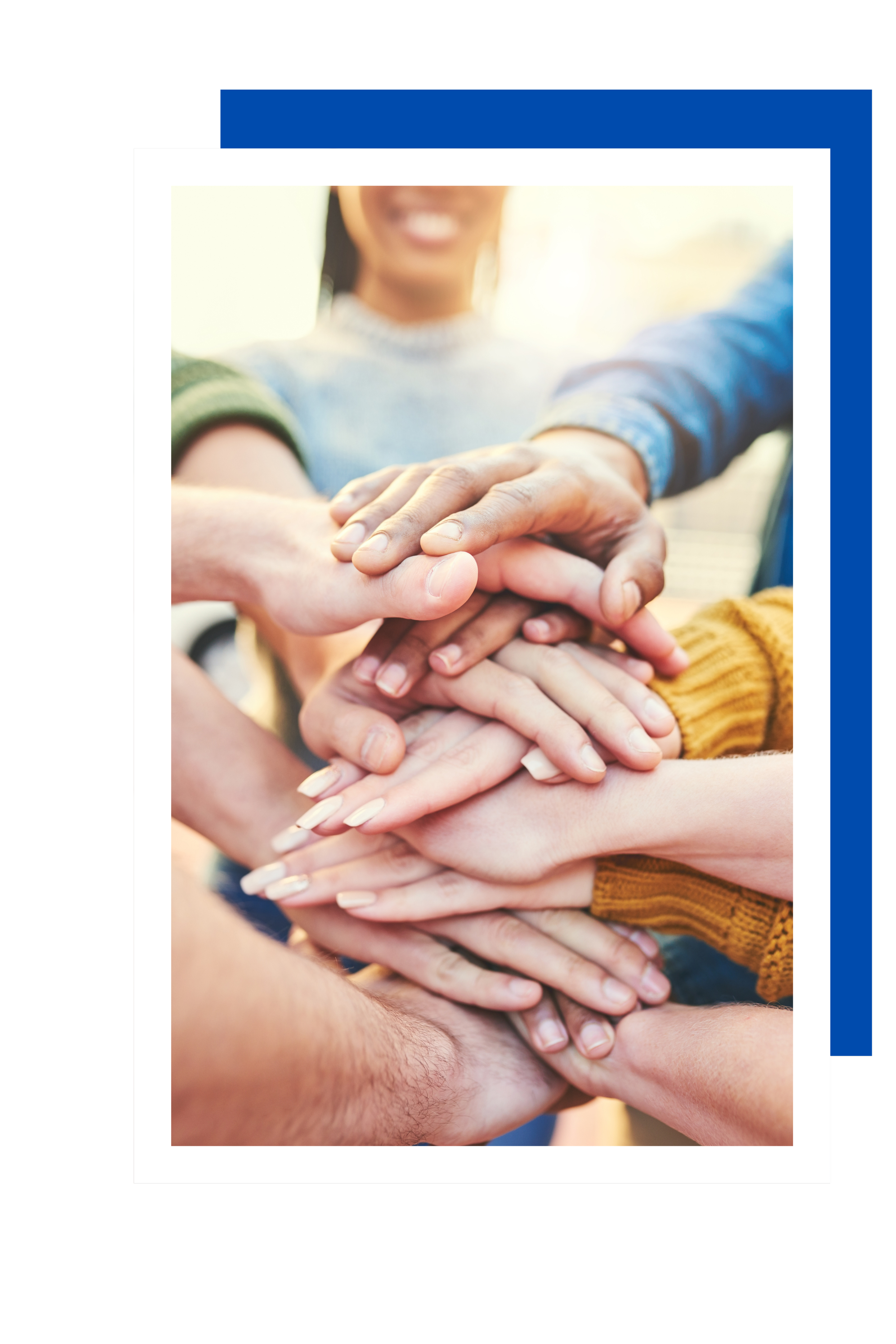 Multiple hands stacked together, symbolizing teamwork and unity, with smiling faces of diverse people in the background.