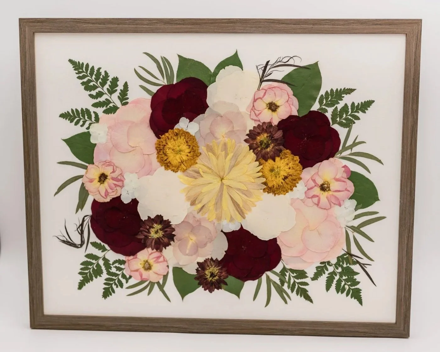 Framed floral artwork featuring various colorful flowers and green leaves.
