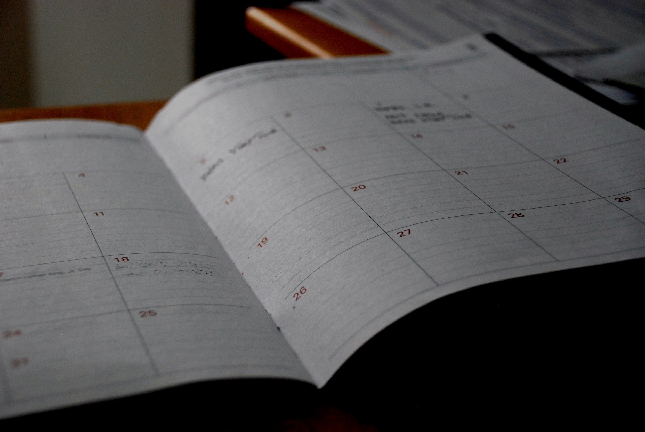 An open planner or calendar on a table, showing dates and weekly pages.