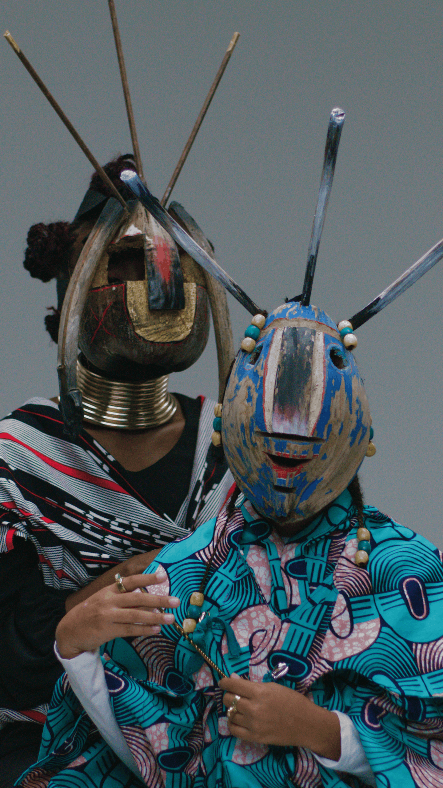 Two people wearing colorful vejigante masks and traditional clothing, participating in a cultural event.
