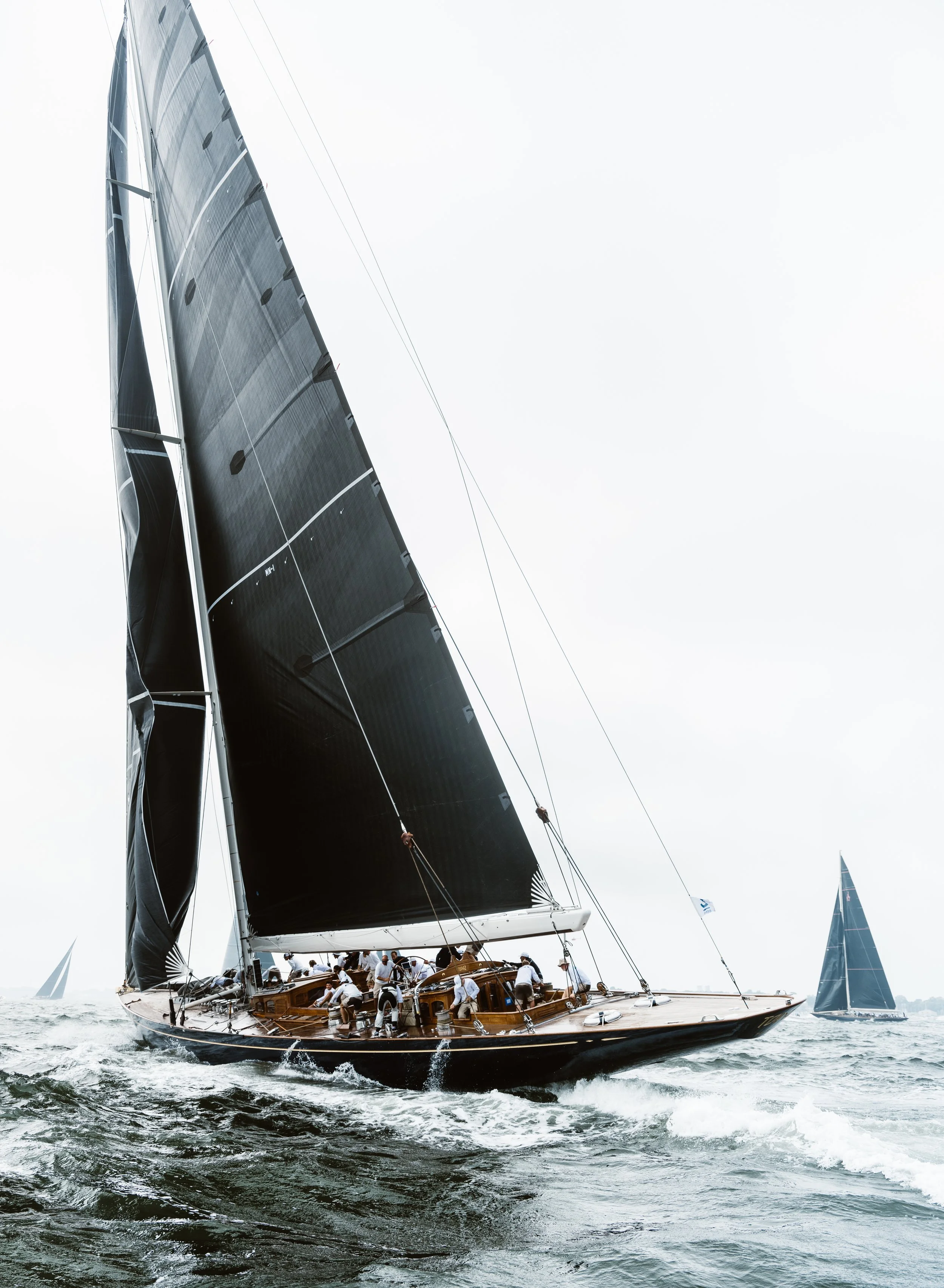 Sailboat in rough sea with crew adjusting sails