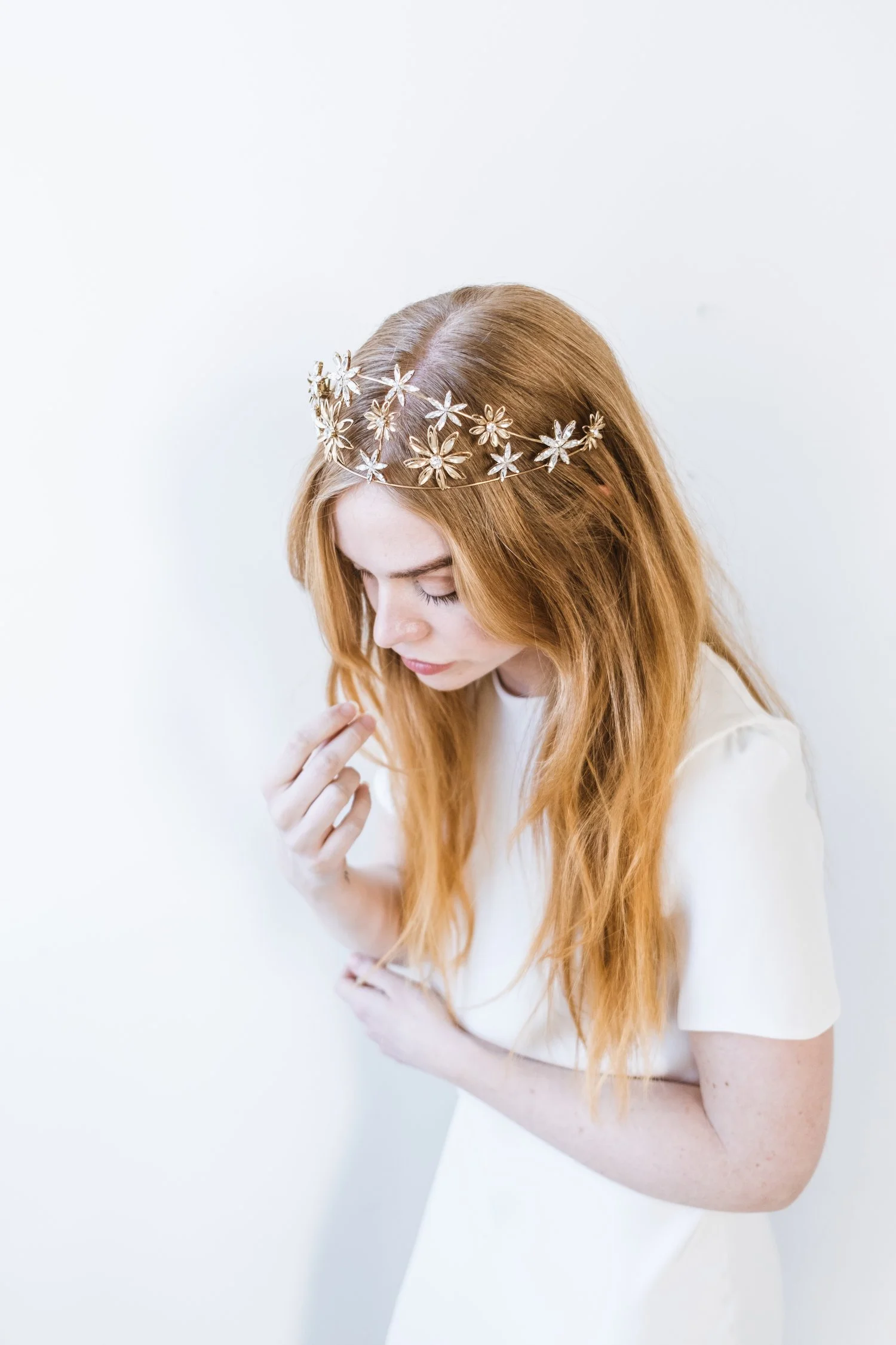 Woman with long red hair wearing a floral crown and white dress