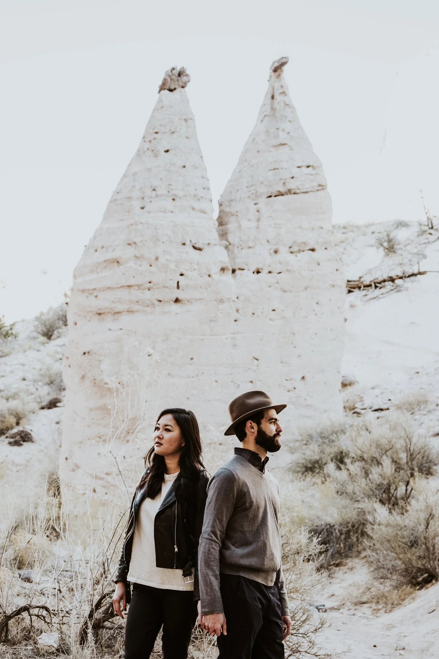 Man and woman standing in front of rock formations in desert landscape