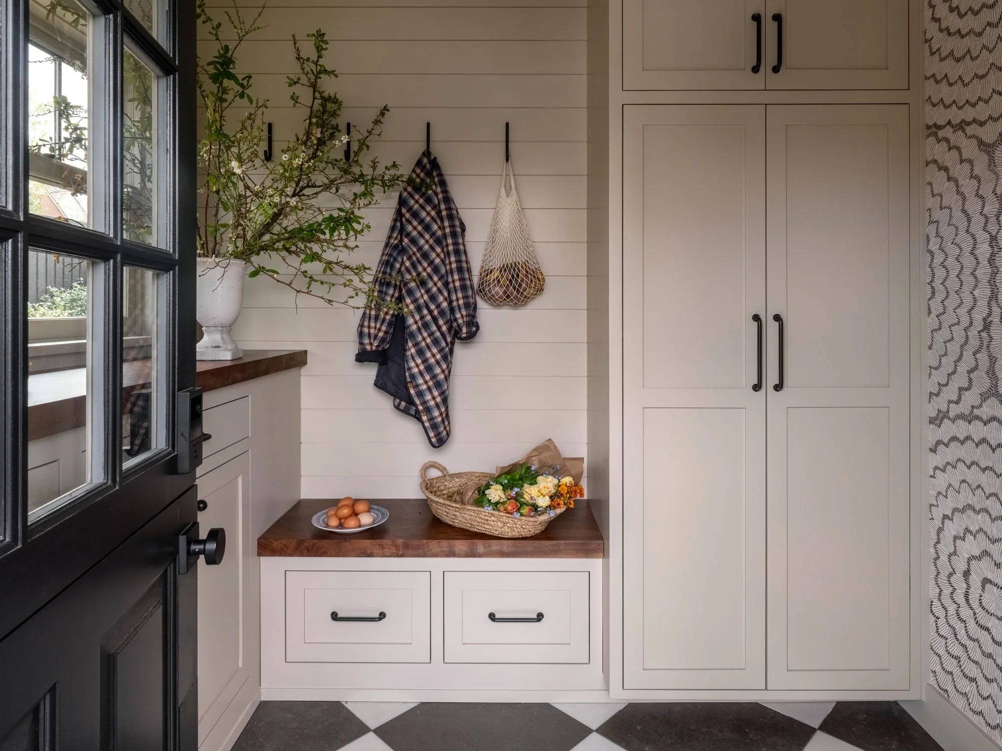 Kitchen corner with white cabinets, dark countertop, a basket of flowers, a plate of eggs, and a window with view outside.