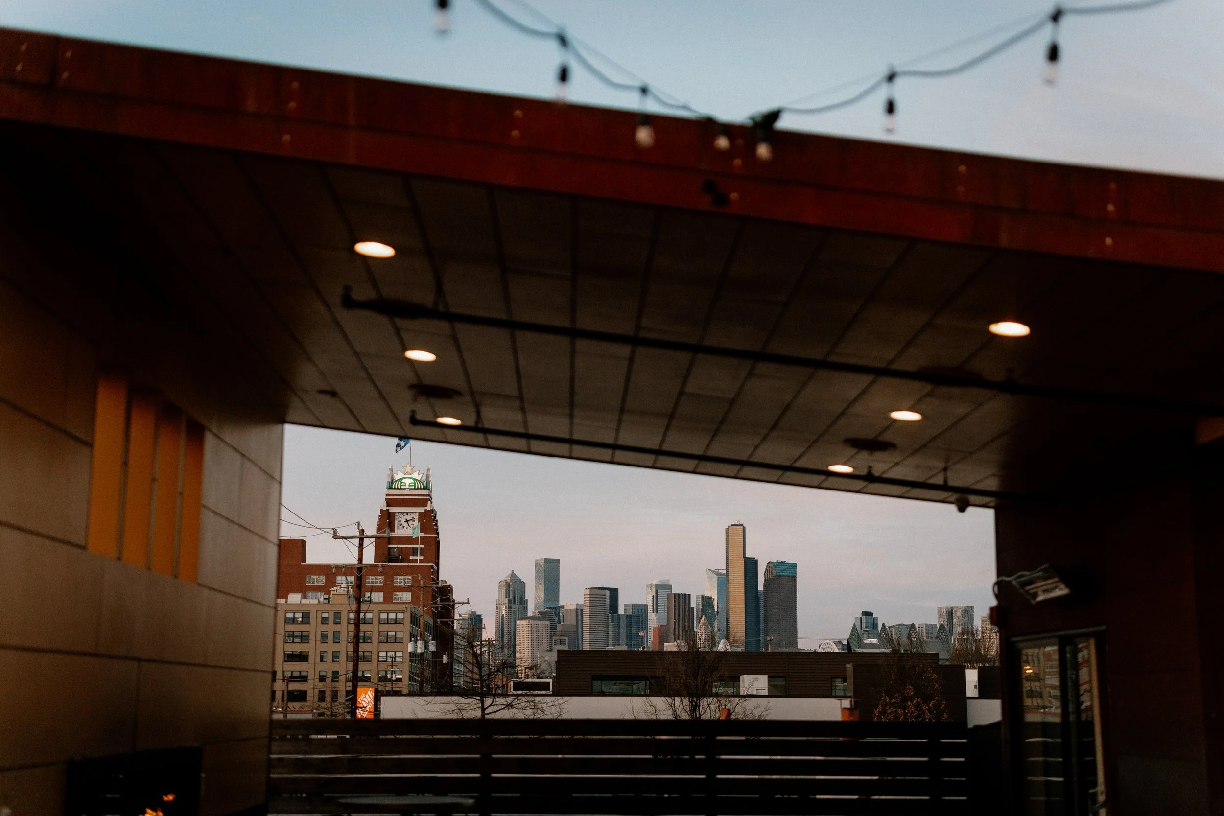 Seattle skyline view from WithinSodo rooftop deck with string lights and covered outdoor space
