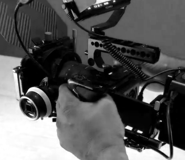 Close-up of a camera mounted on a stabilizer or rig, with a person's hand adjusting it.