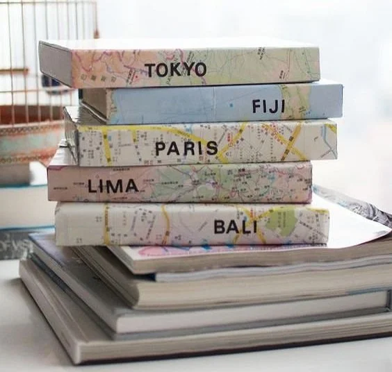 stack of travel scrapbooks wrapped in maps