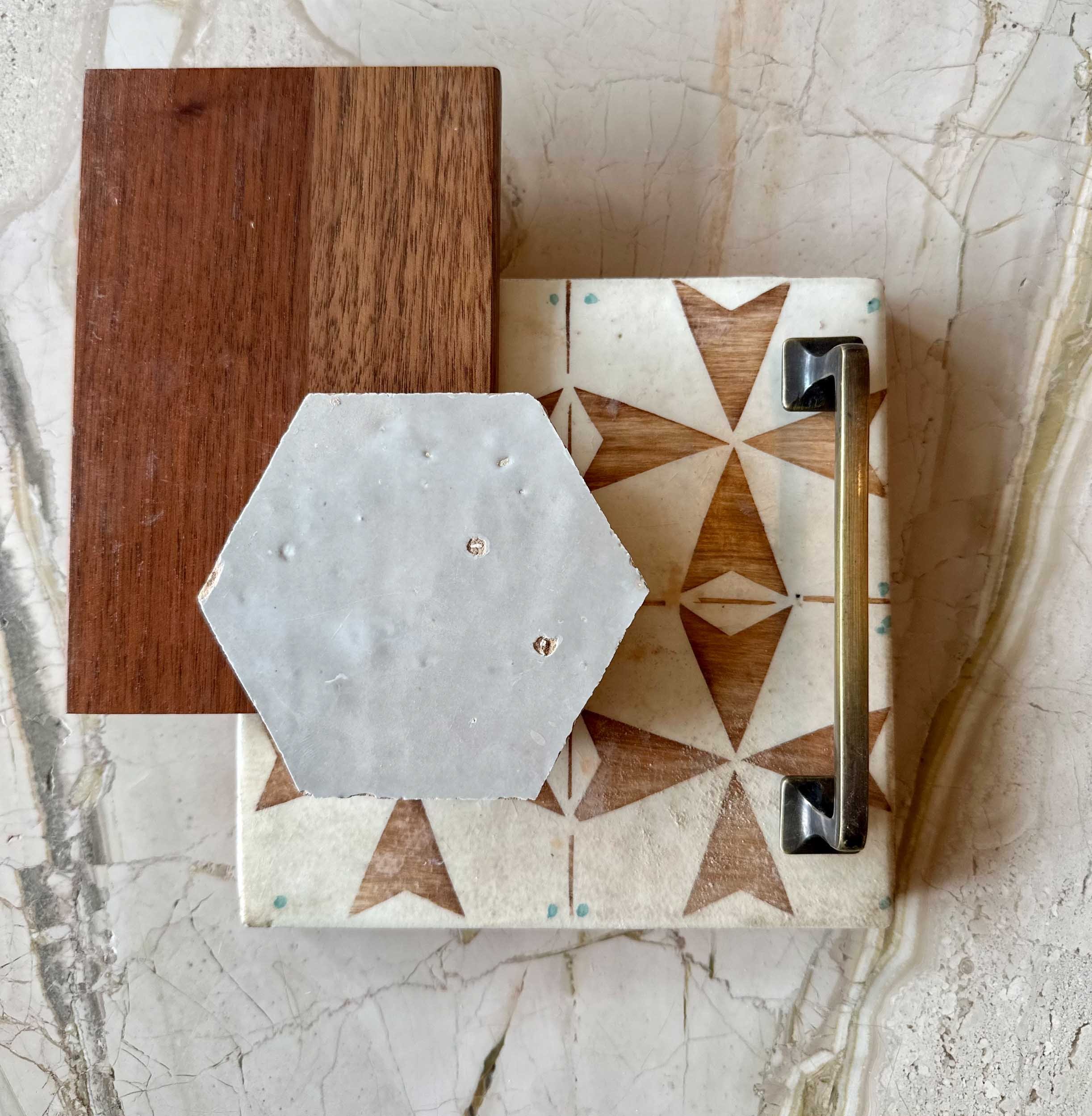 Flatlay of patterned tiles, drawer pulls, warm wood and mosaic