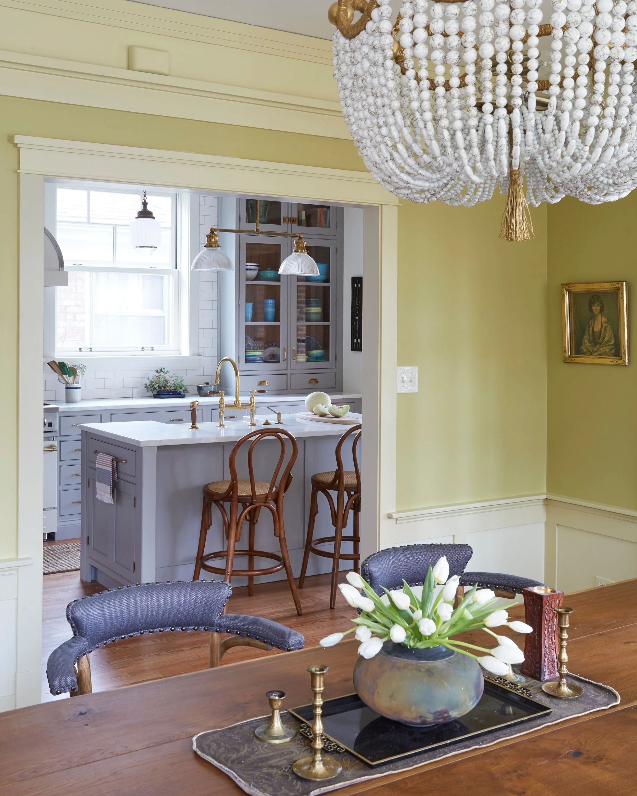 KitchenLab Interiors finished Sunnyside kitchen with light gray kitchen island, white marble countertops, dark maple wood floors, and brass vintage light fixtures