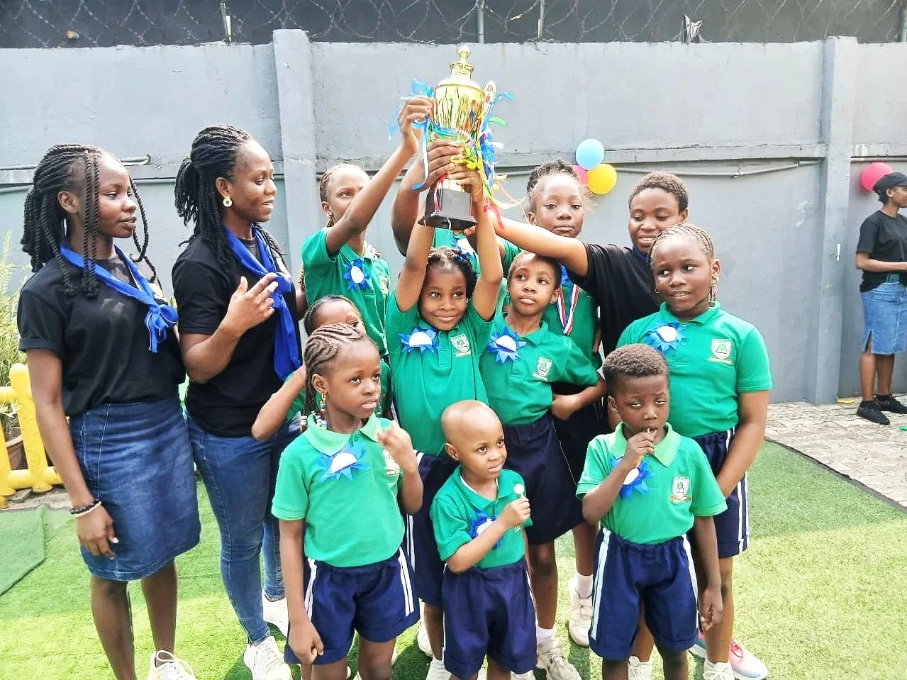 Group of students celebrating with a trophy at a Fels Idea Academy school sports event.