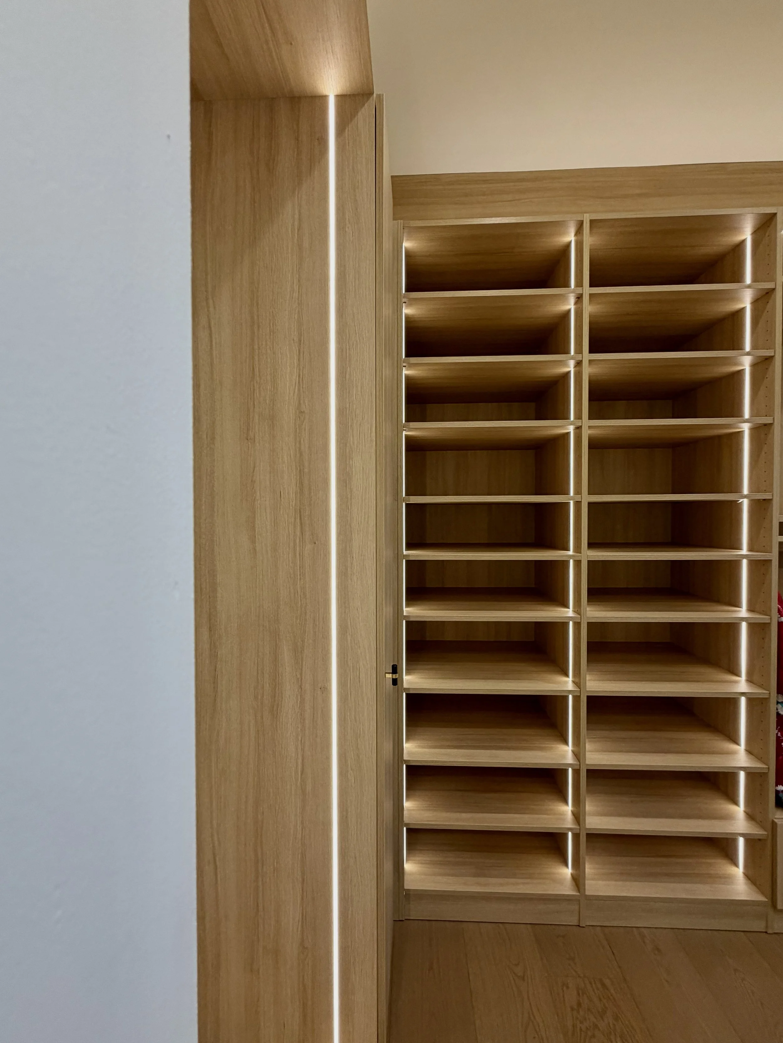 Master walk in closet, rift oak, integrated lighting on vertical panels, above closet lighting