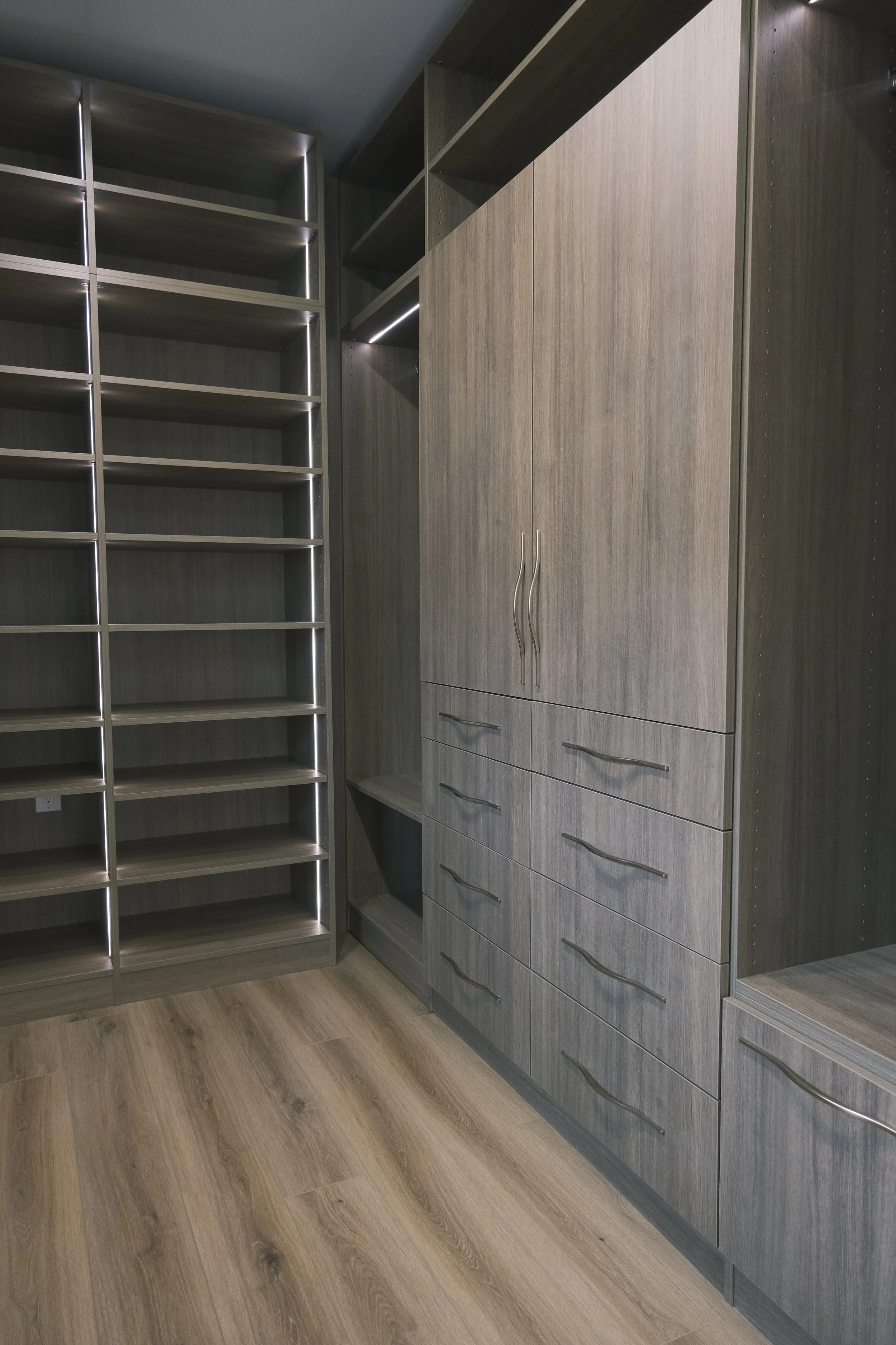 Master walk in closet, dark wood, drawers, integrated lighting, closed storage doors