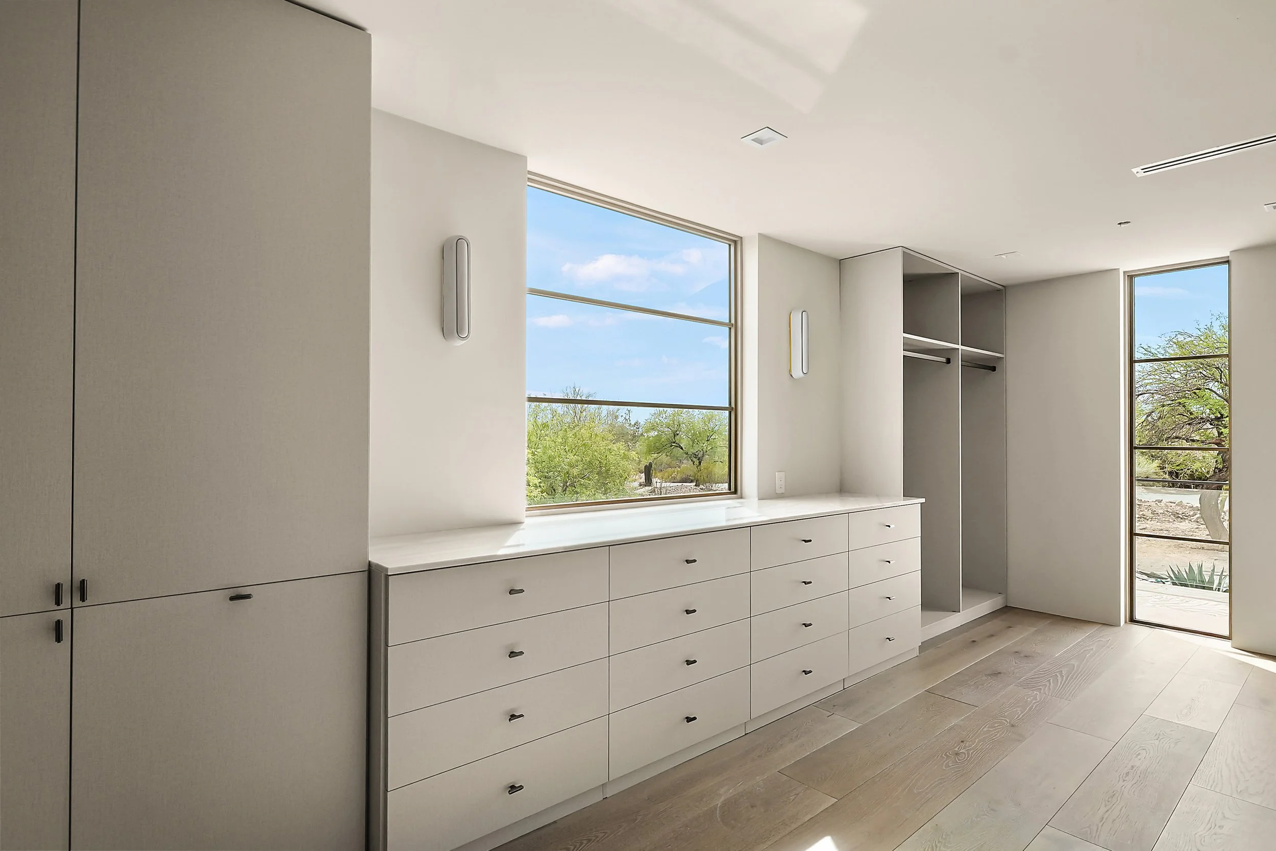 Premium modern walk-in closet engineered and installed in Paradise Valley. High-end frameless storage systems featuring minimalist flat-panel drawer stacks and integrated wardrobe hanging configurations. Collaborative engineering from designer concep