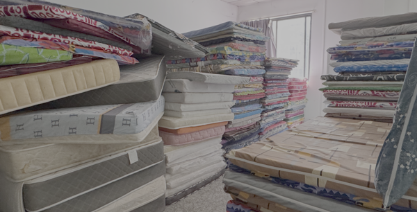 A room full of hundeds of mattresses, neatly stacked in an abandoned scam compound.